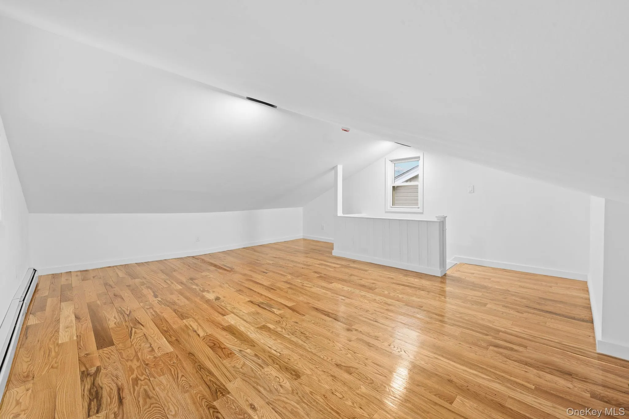 Bonus room with light wood-style floors, a baseboard radiator, and vaulted ceiling Bonus room with light wood-style floors, a baseboard radiator, and vaulted ceiling