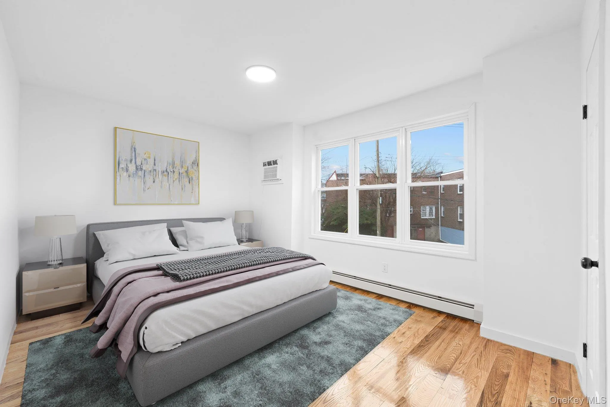 Bedroom with a baseboard heating unit, light wood-style floors, and a wall mounted AC Bedroom with a baseboard heating unit, light wood-style floors, and a wall mounted AC