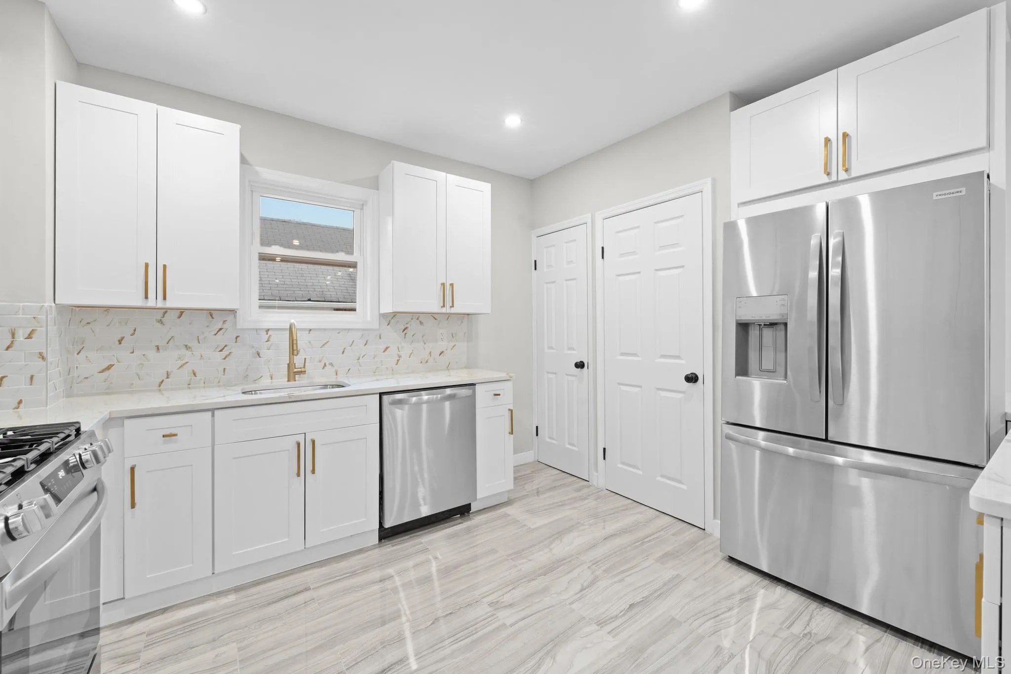 Kitchen with appliances with stainless steel finishes, white cabinetry, light stone countertops, tasteful backsplash, and recessed lighting Kitchen with appliances with stainless steel finishes, white cabinetry, light stone countertops, tasteful backsplash, and recessed lighting