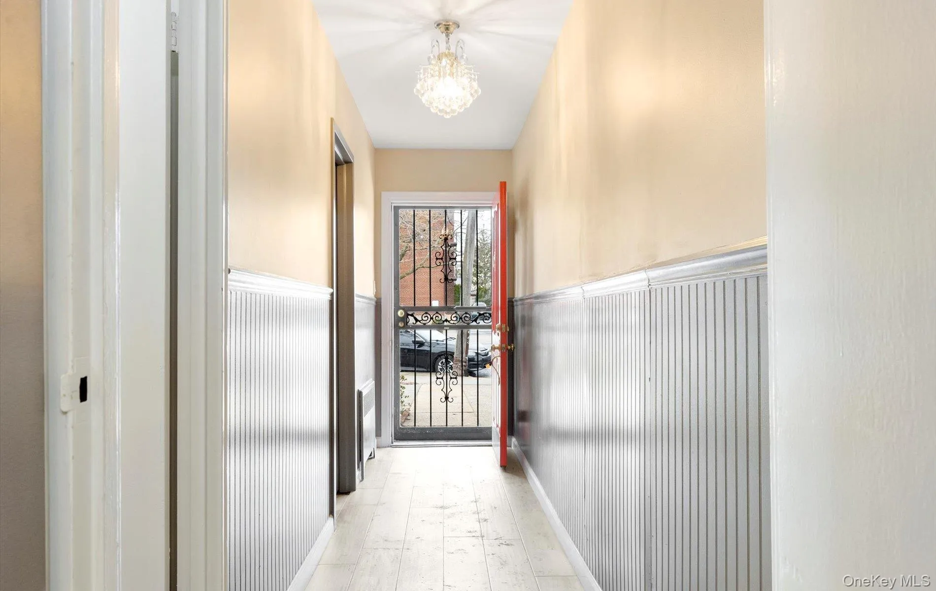 Hallway with a wainscoted wall, a chandelier, and light wood-type flooring Hallway with a wainscoted wall, a chandelier, and light wood-type flooring