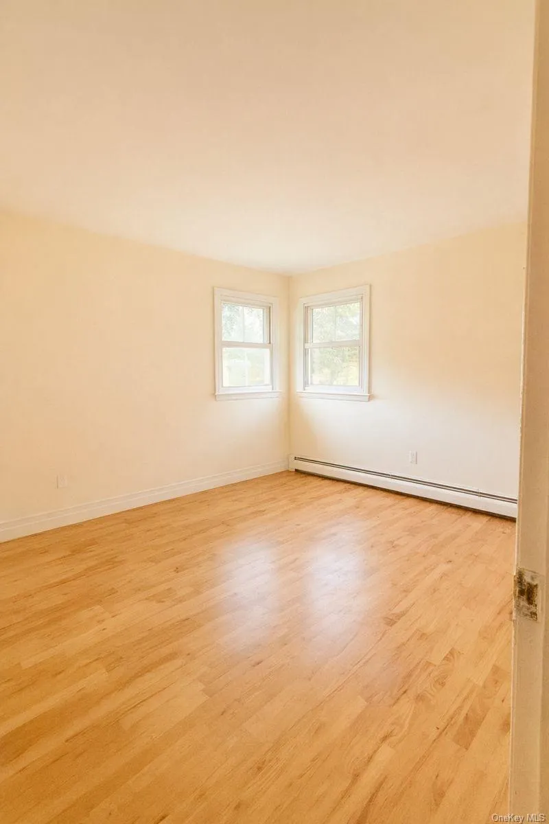 Unfurnished room with light wood-style flooring and a baseboard heating unit Unfurnished room with light wood-style flooring and a baseboard heating unit