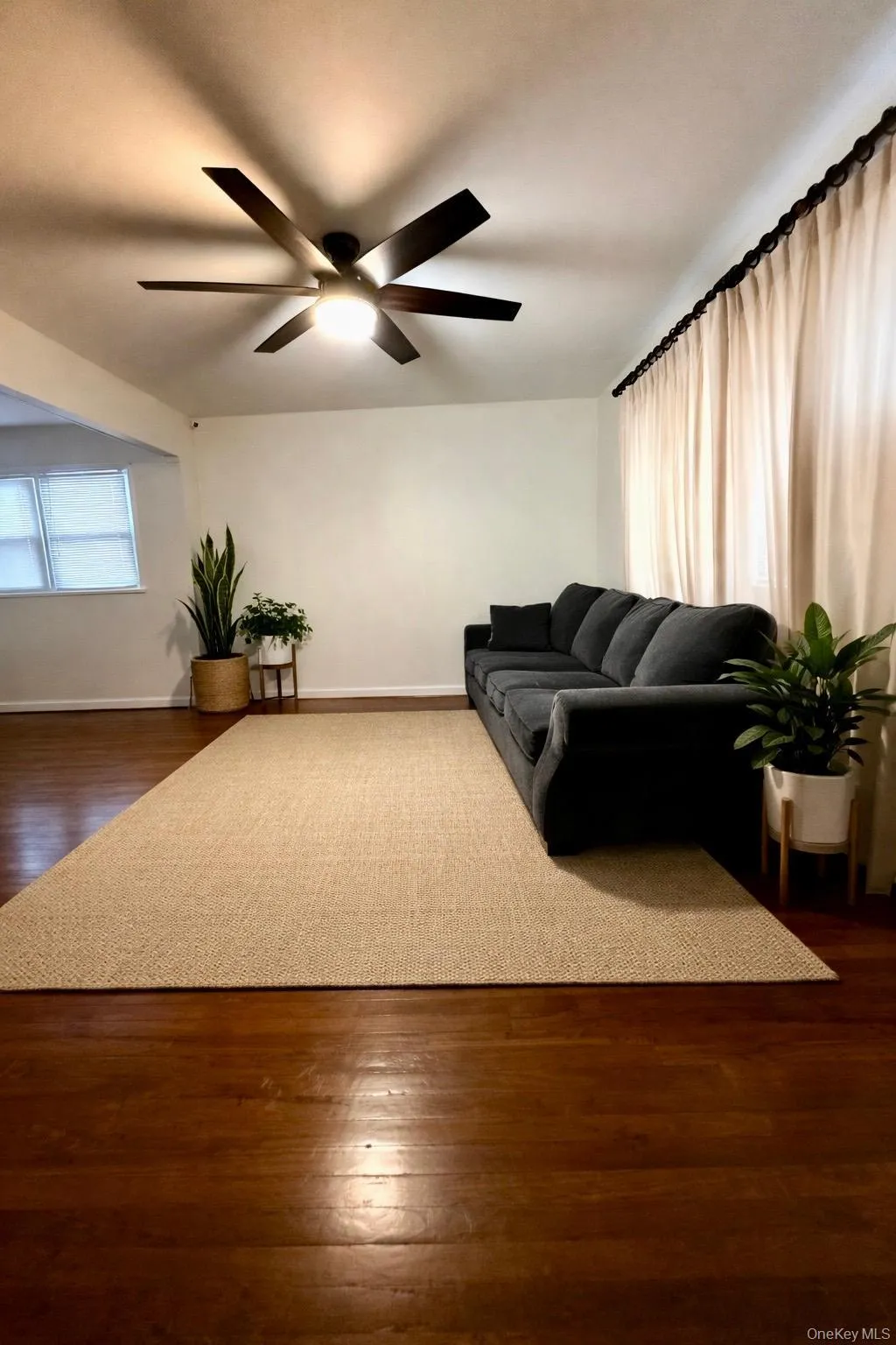 Living area featuring dark wood-type flooring and a ceiling fan Living area featuring dark wood-type flooring and a ceiling fan