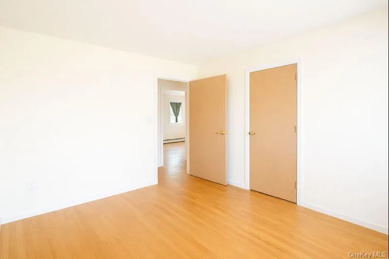 Unfurnished bedroom featuring light wood-type flooring and baseboard heating Unfurnished bedroom featuring light wood-type flooring and baseboard heating