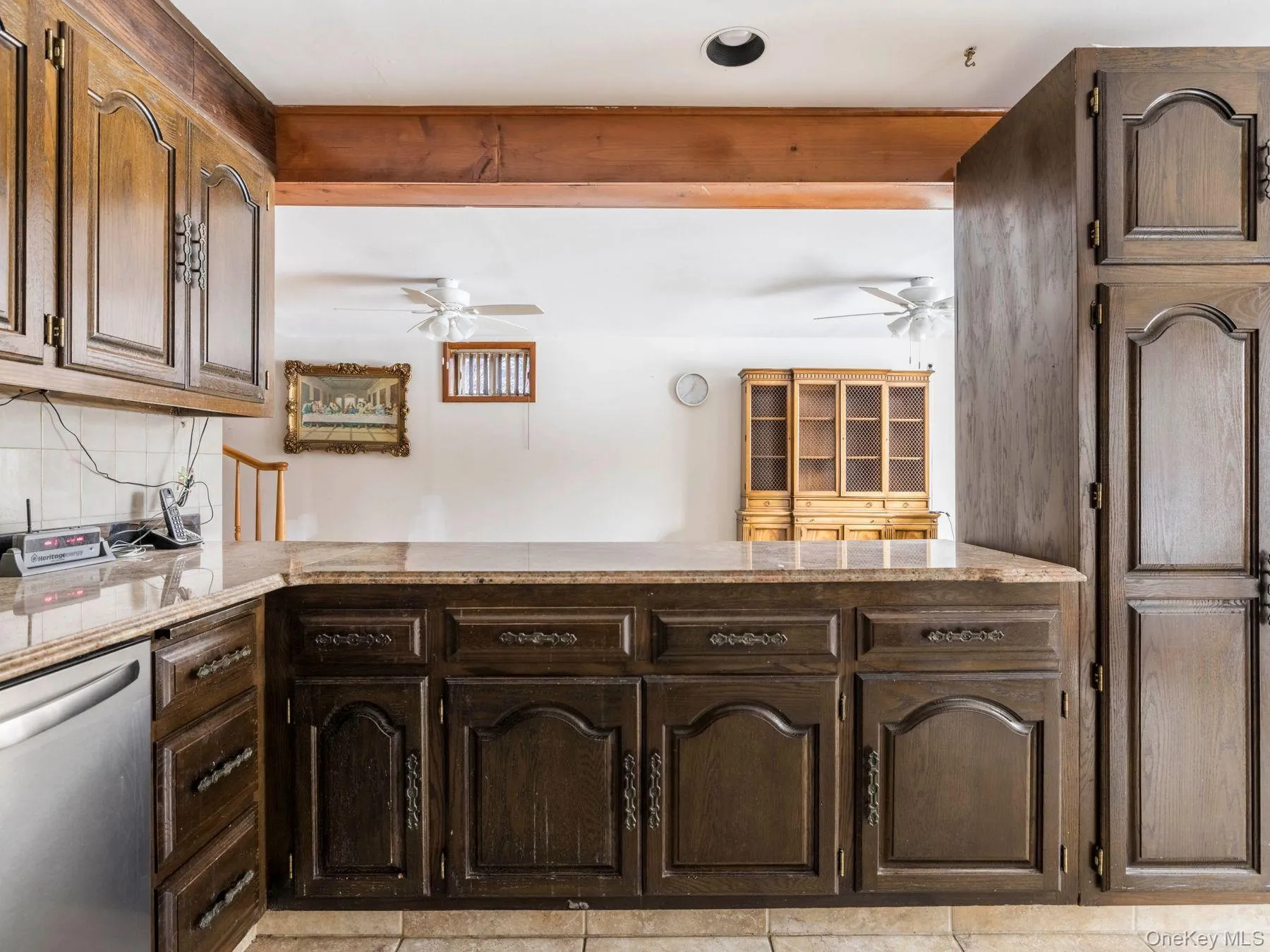 Kitchen with stainless steel dishwasher, dark brown cabinetry, a peninsula, decorative backsplash, and a ceiling fan Kitchen with stainless steel dishwasher, dark brown cabinetry, a peninsula, decorative backsplash, and a ceiling fan