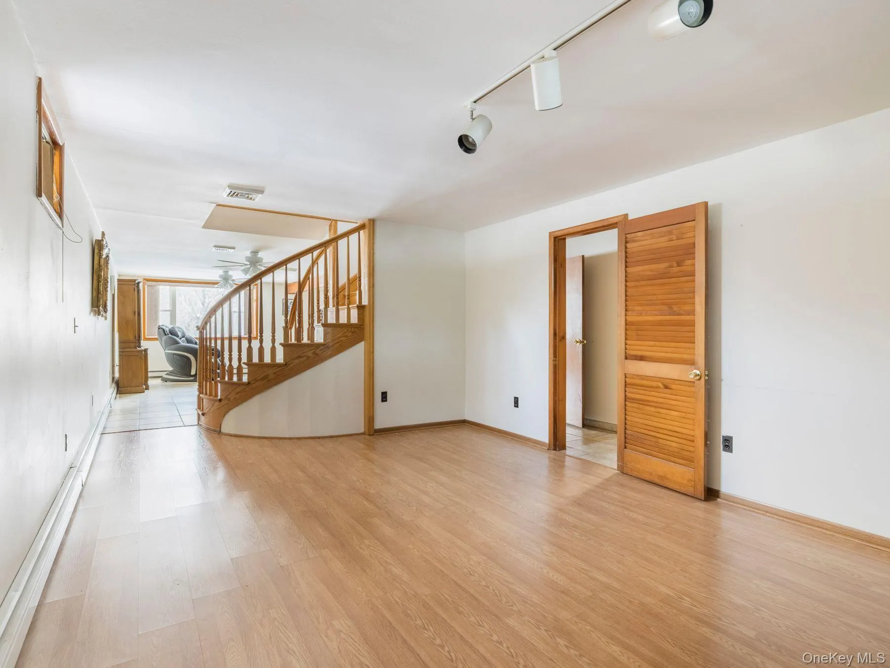 Empty room with stairs, rail lighting, and light wood-style floors Empty room with stairs, rail lighting, and light wood-style floors