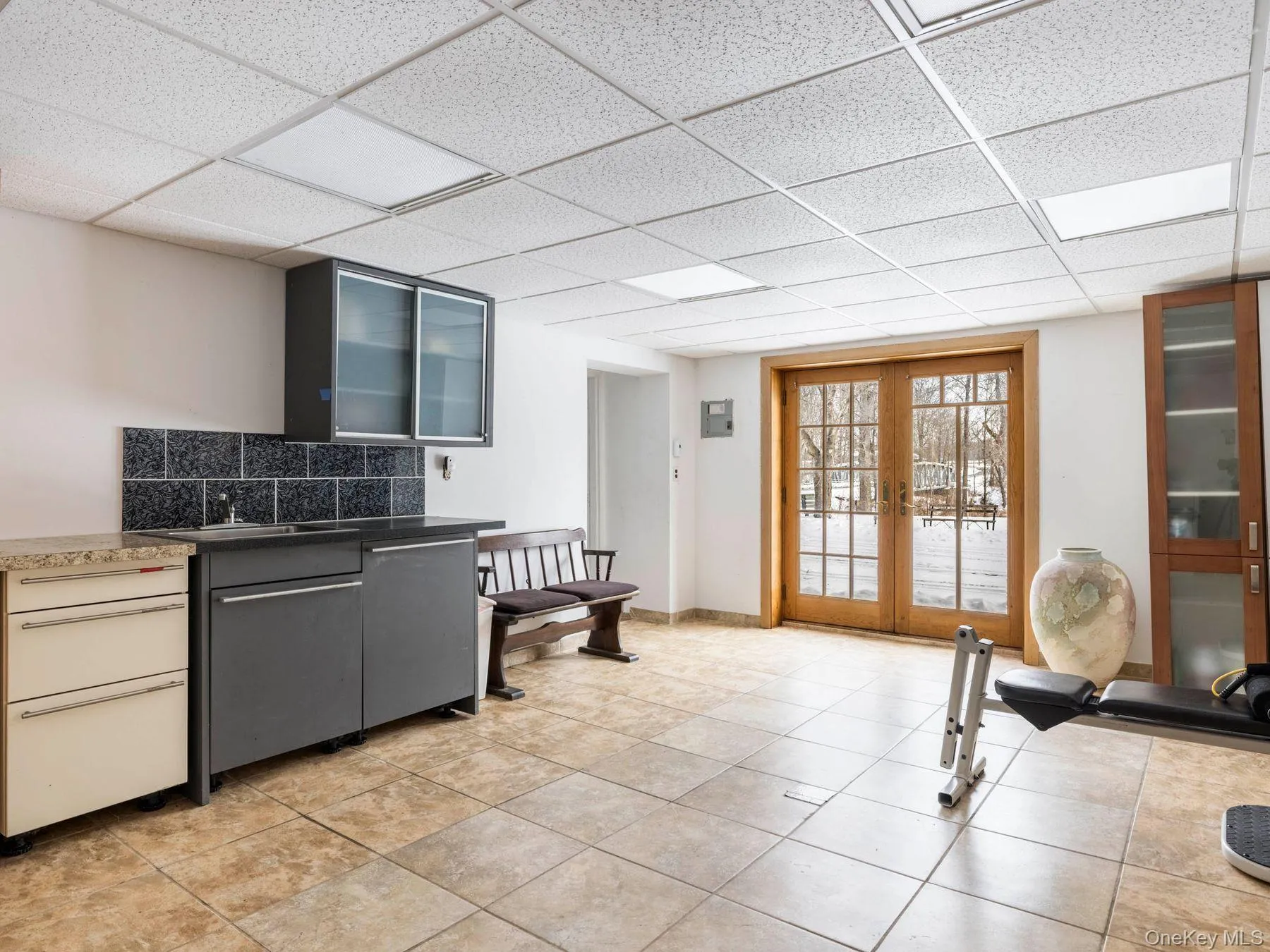Kitchen featuring tasteful backsplash, glass insert cabinets, french doors, dark countertops, and a paneled ceiling Kitchen featuring tasteful backsplash, glass insert cabinets, french doors, dark countertops, and a paneled ceiling