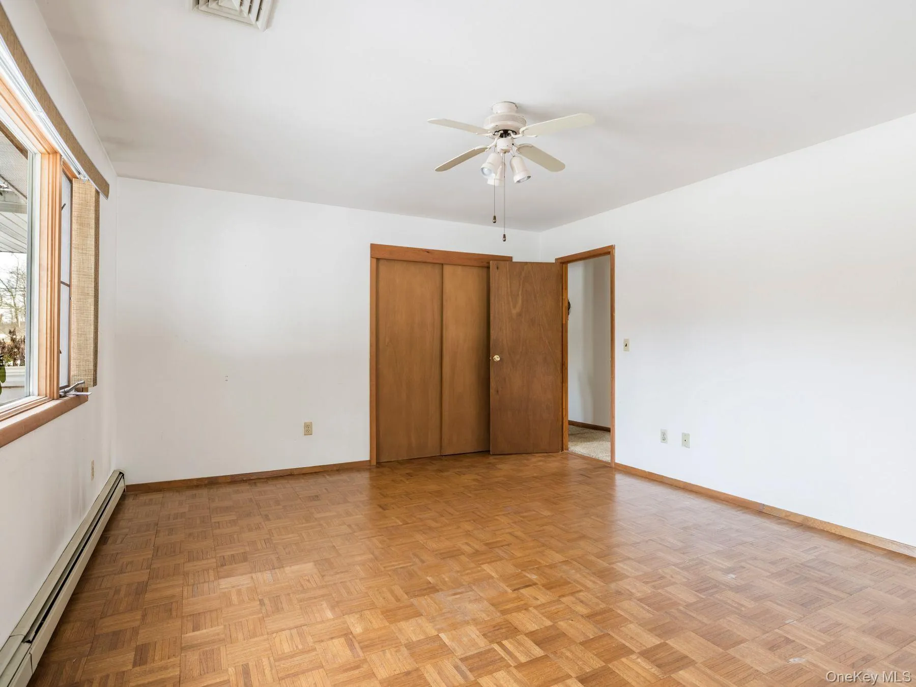 Unfurnished bedroom featuring a baseboard radiator, a closet, and ceiling fan Unfurnished bedroom featuring a baseboard radiator, a closet, and ceiling fan