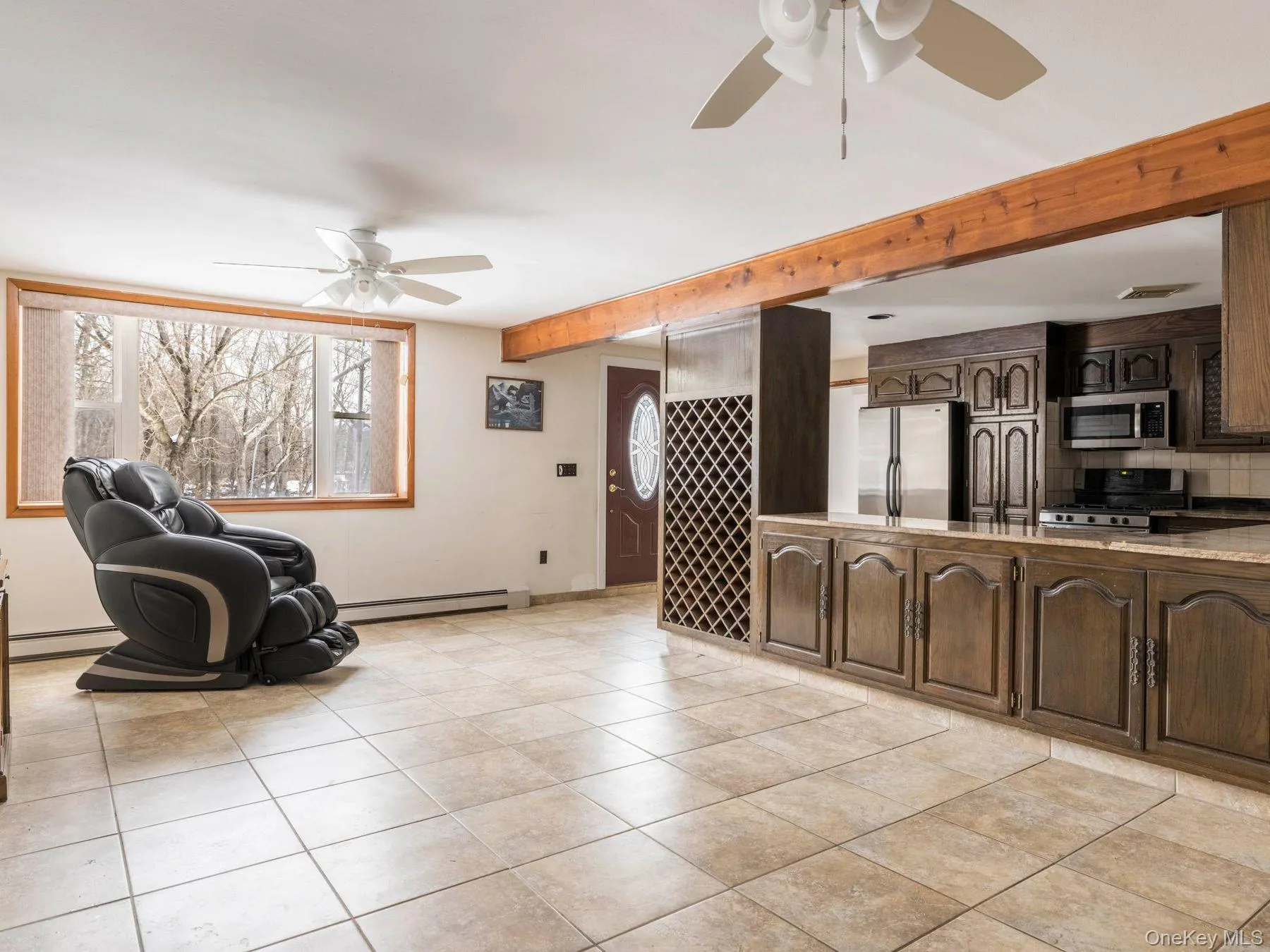 Unfurnished living room featuring a ceiling fan, beam ceiling, light tile patterned flooring, and baseboard heating Unfurnished living room featuring a ceiling fan, beam ceiling, light tile patterned flooring, and baseboard heating
