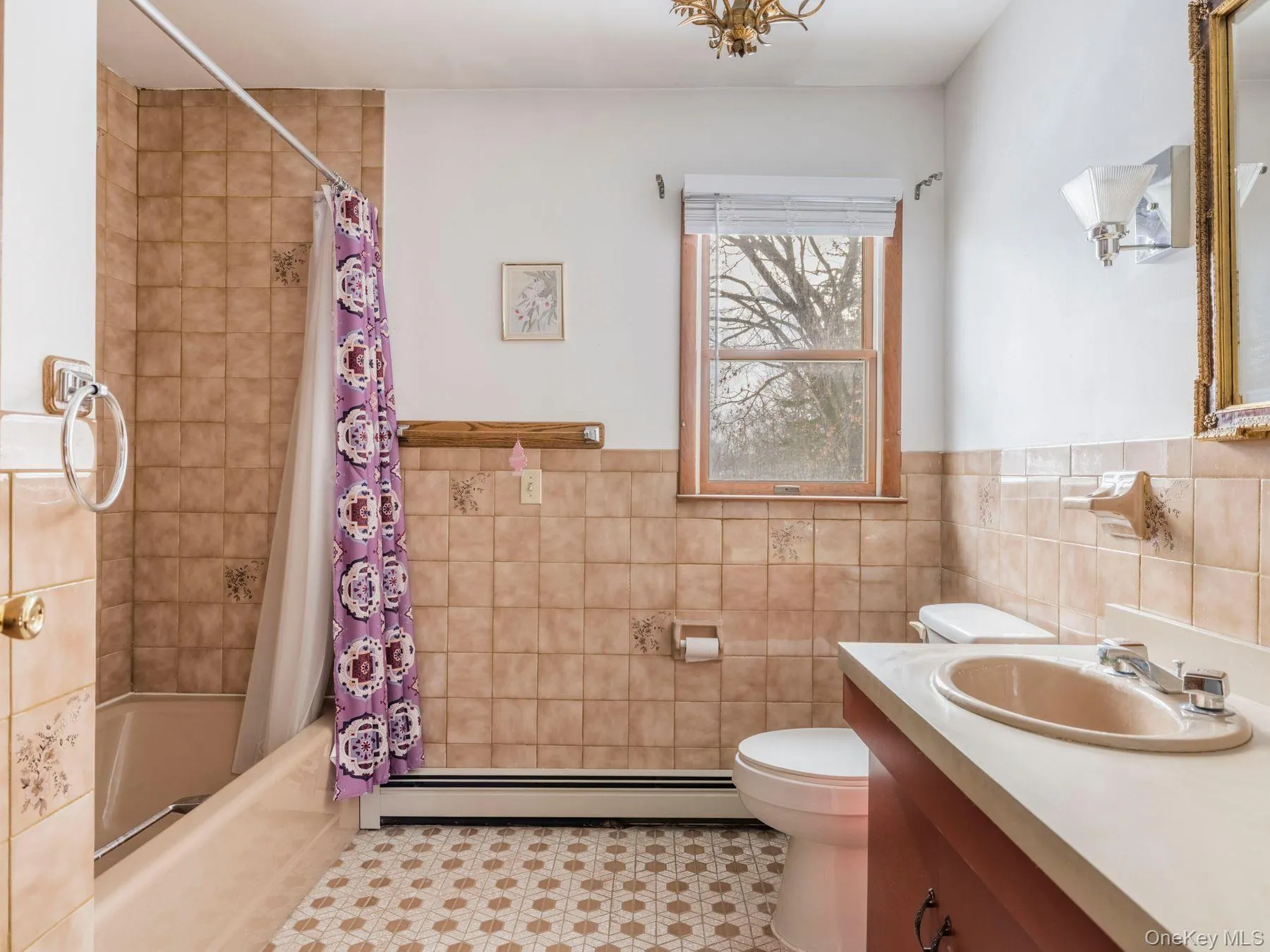 Bathroom featuring shower / bathtub combination with curtain, vanity, a baseboard heating unit, tile walls, and wainscoting Bathroom featuring shower / bathtub combination with curtain, vanity, a baseboard heating unit, tile walls, and wainscoting