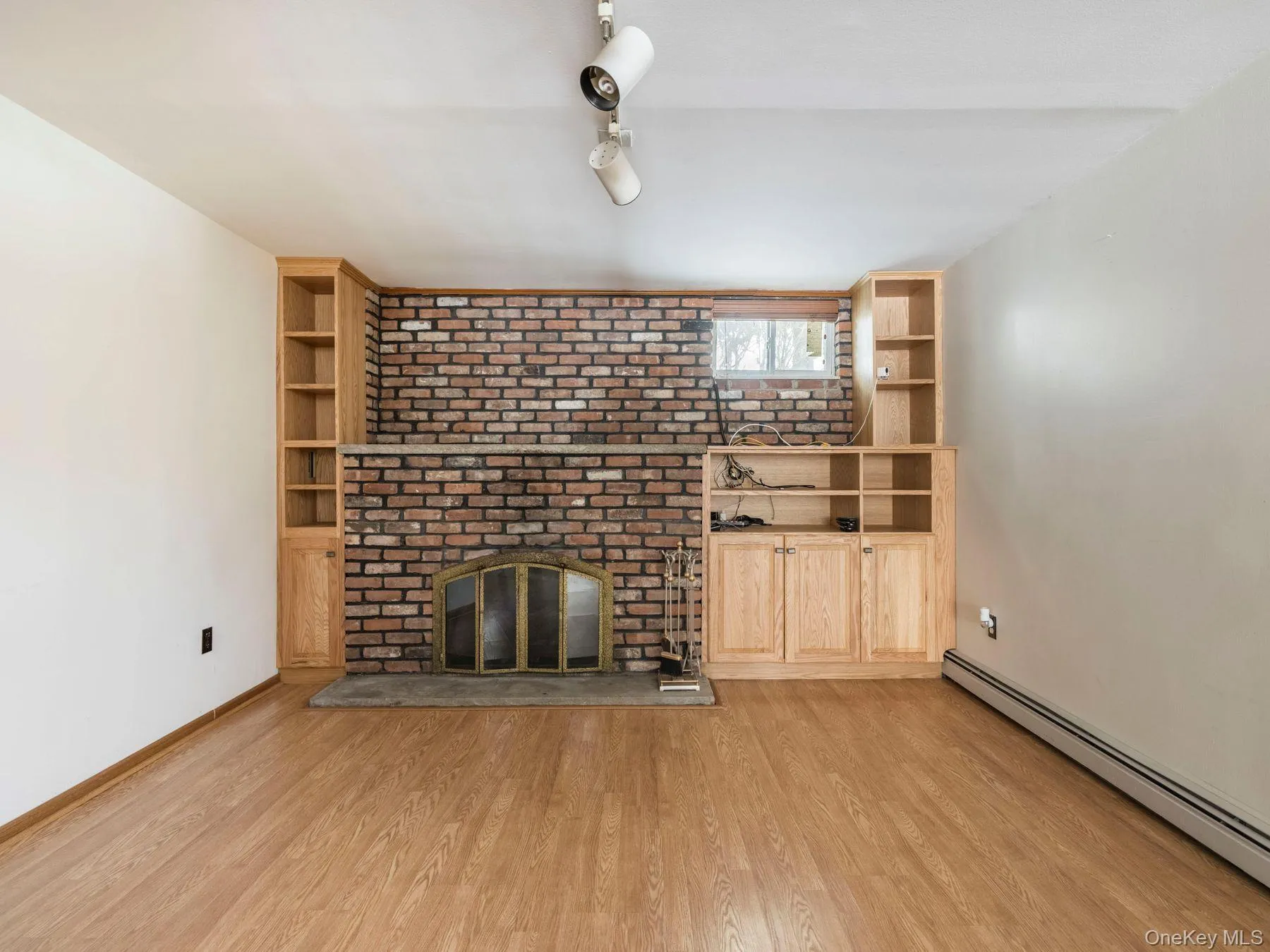 Unfurnished living room with a baseboard heating unit, light wood-style floors, and a fireplace Unfurnished living room with a baseboard heating unit, light wood-style floors, and a fireplace