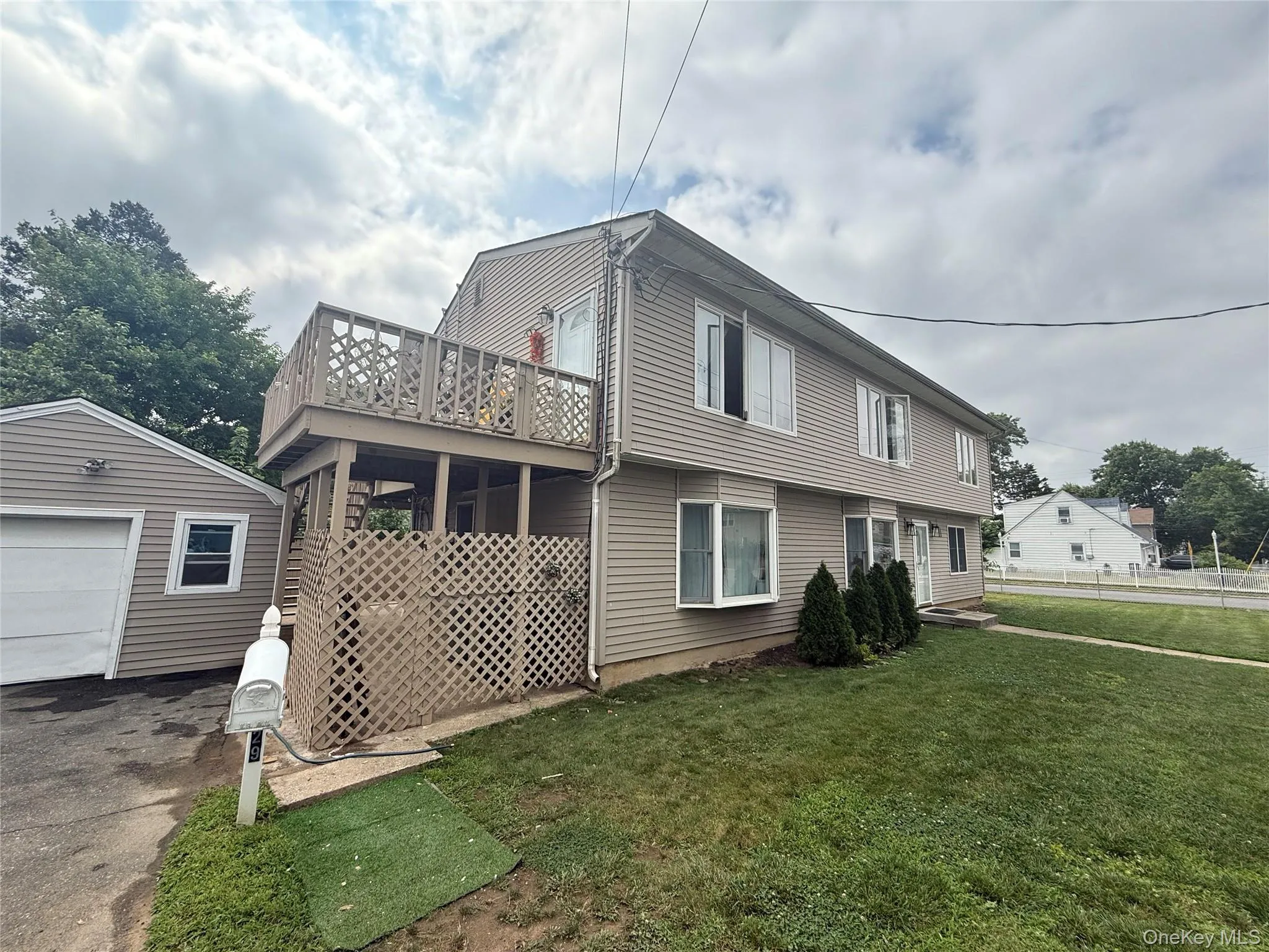 View of side of property featuring an outdoor structure, a lawn, driveway, and a garage View of side of property featuring an outdoor structure, a lawn, driveway, and a garage