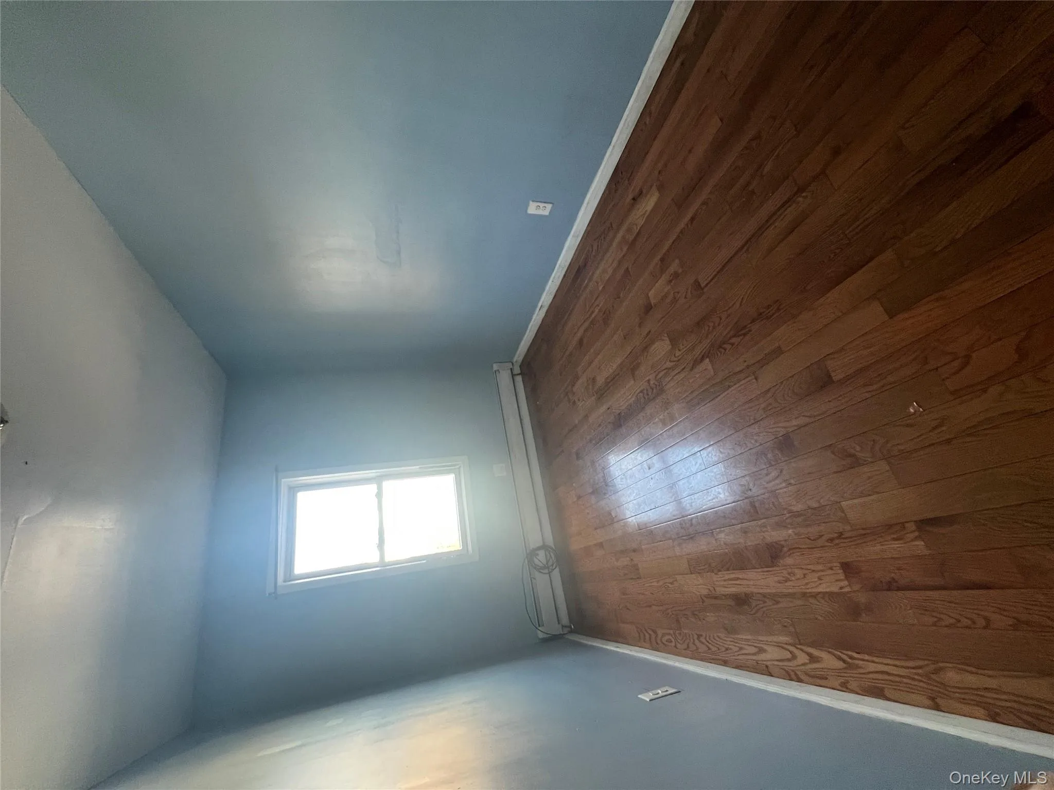 Empty room with a baseboard radiator and dark wood-style flooring Empty room with a baseboard radiator and dark wood-style flooring