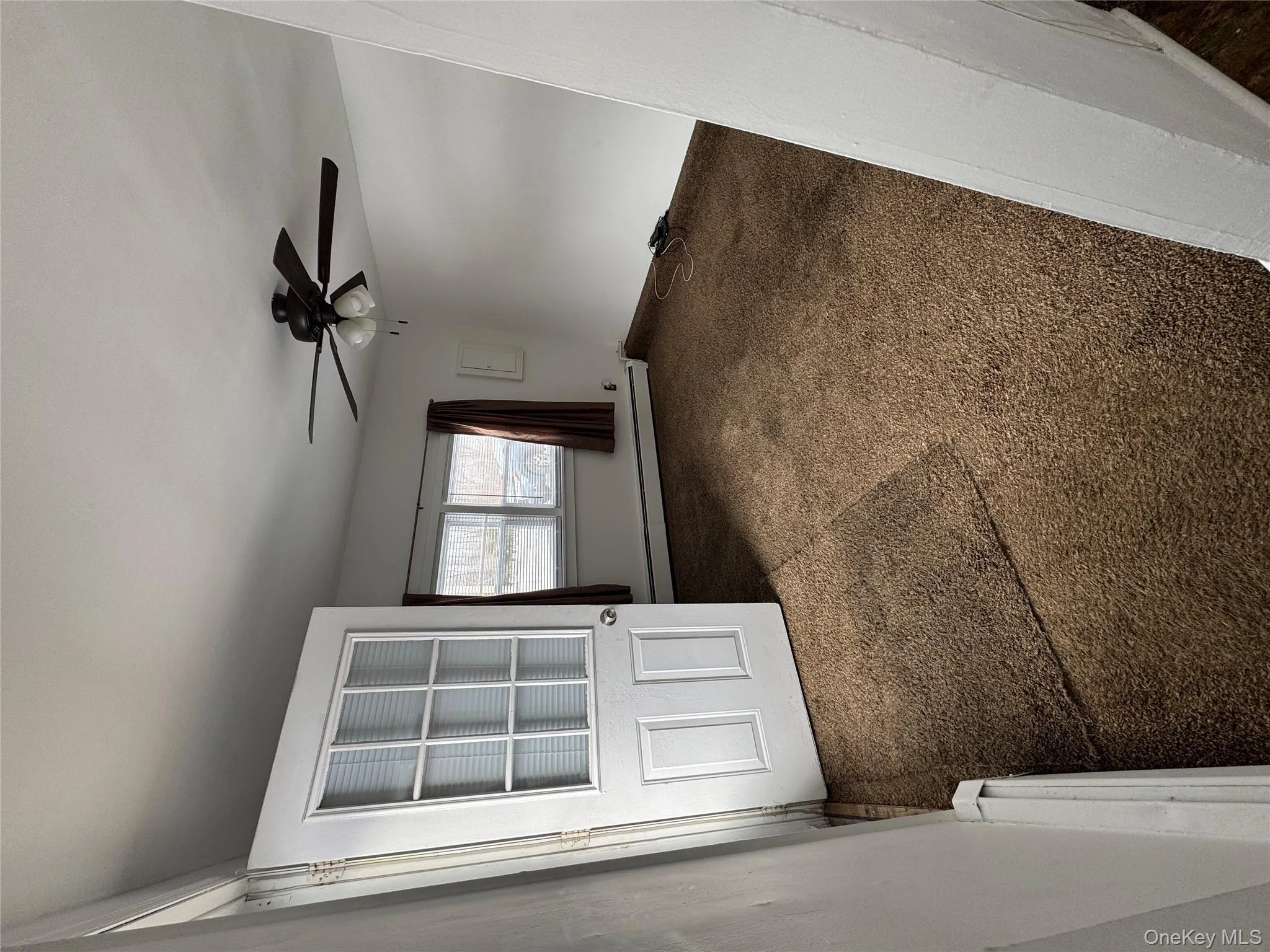 Carpeted empty room featuring a baseboard heating unit and a ceiling fan Carpeted empty room featuring a baseboard heating unit and a ceiling fan