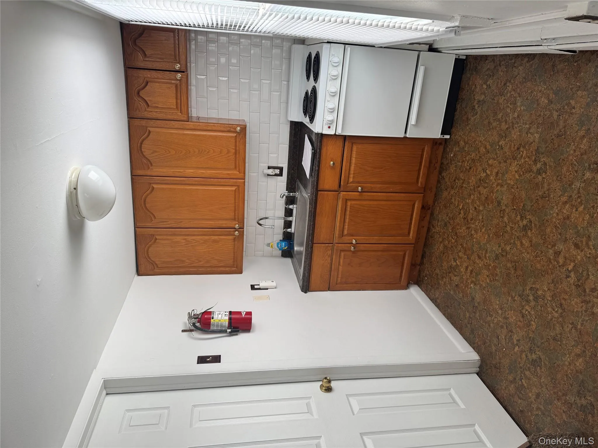 Kitchen featuring range, brown cabinetry, dark countertops, tasteful backsplash, and baseboard heating Kitchen featuring range, brown cabinetry, dark countertops, tasteful backsplash, and baseboard heating