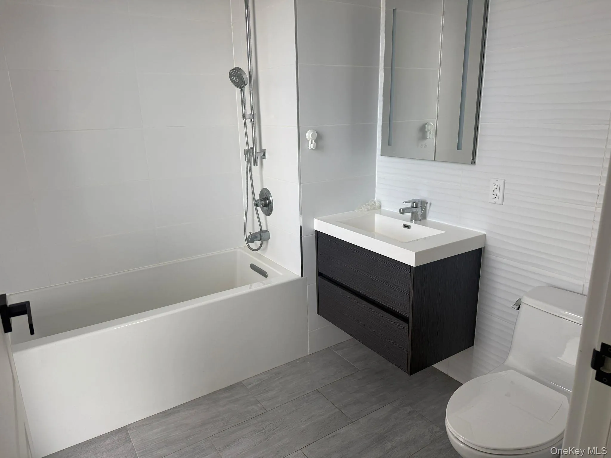Full bath featuring vanity, shower / bathtub combination, tile walls, and tile patterned floors Full bath featuring vanity, shower / bathtub combination, tile walls, and tile patterned floors