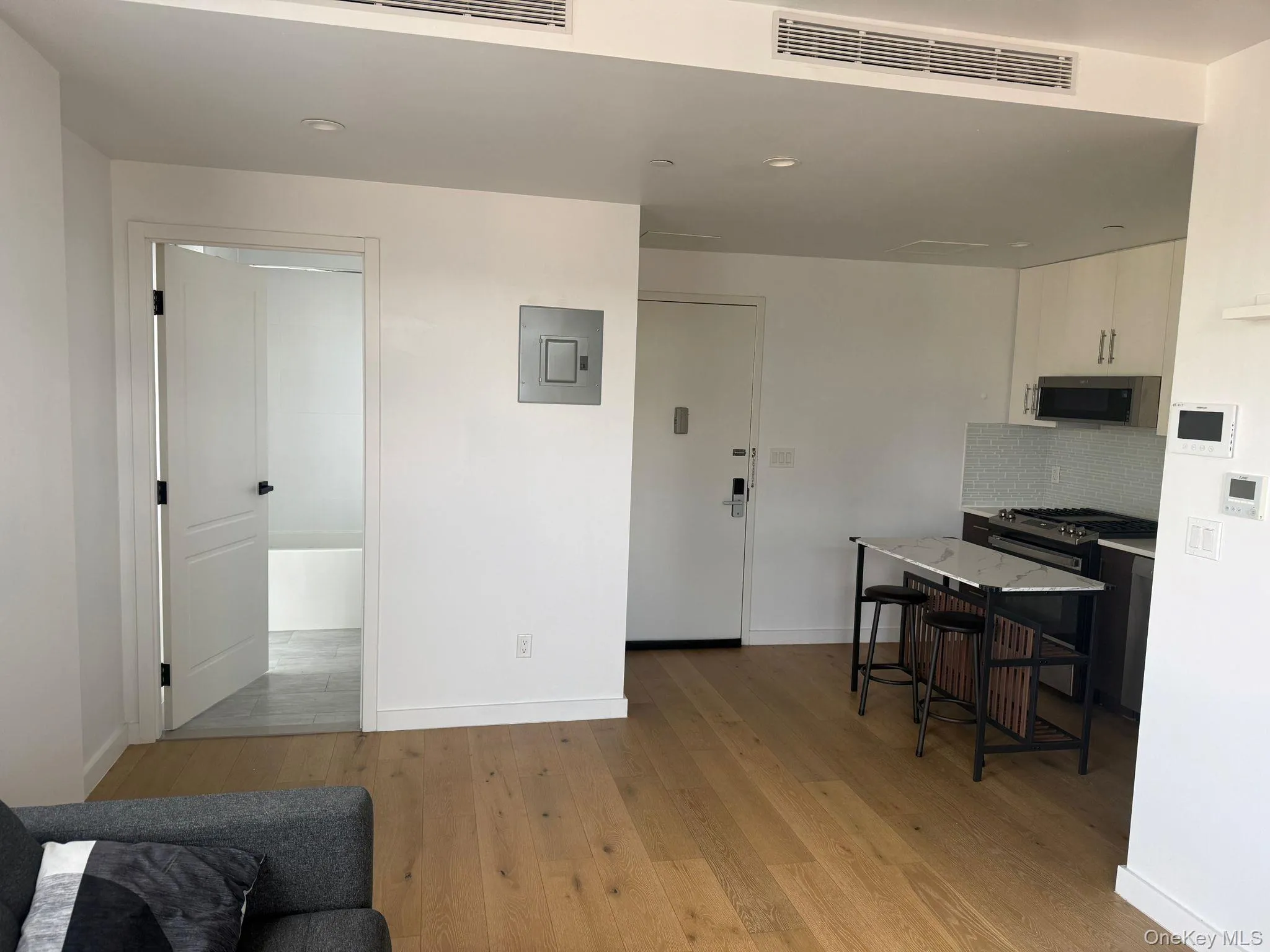 Kitchen featuring a kitchen breakfast bar, light wood-style flooring, gas stove, backsplash, and electric panel Kitchen featuring a kitchen breakfast bar, light wood-style flooring, gas stove, backsplash, and electric panel