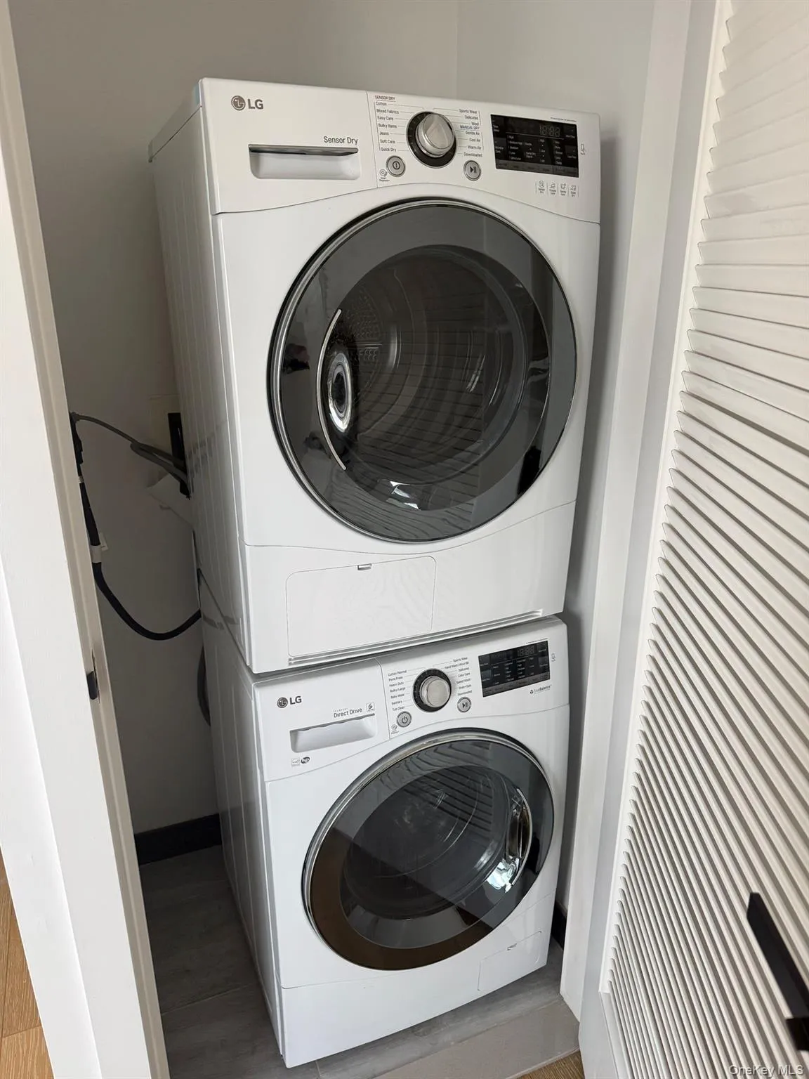 Laundry room with stacked washer / drying machine and wood finished floors Laundry room with stacked washer / drying machine and wood finished floors
