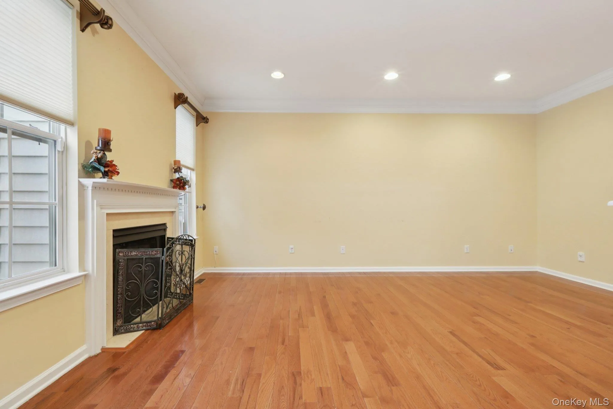 Living room featuring a fireplace, light hardwood-style floors, ornamental molding, and recessed lighting Living room featuring a fireplace, light hardwood-style floors, ornamental molding, and recessed lighting