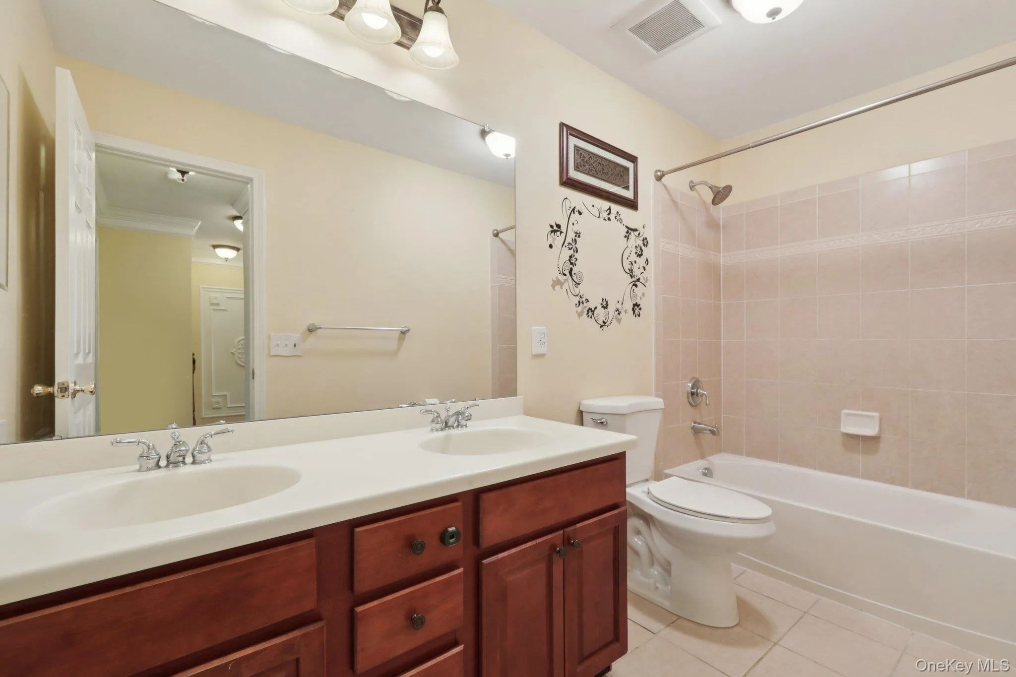 Full bathroom featuring double vanity, tub / shower combination, and light tile patterned flooring Full bathroom featuring double vanity, tub / shower combination, and light tile patterned flooring