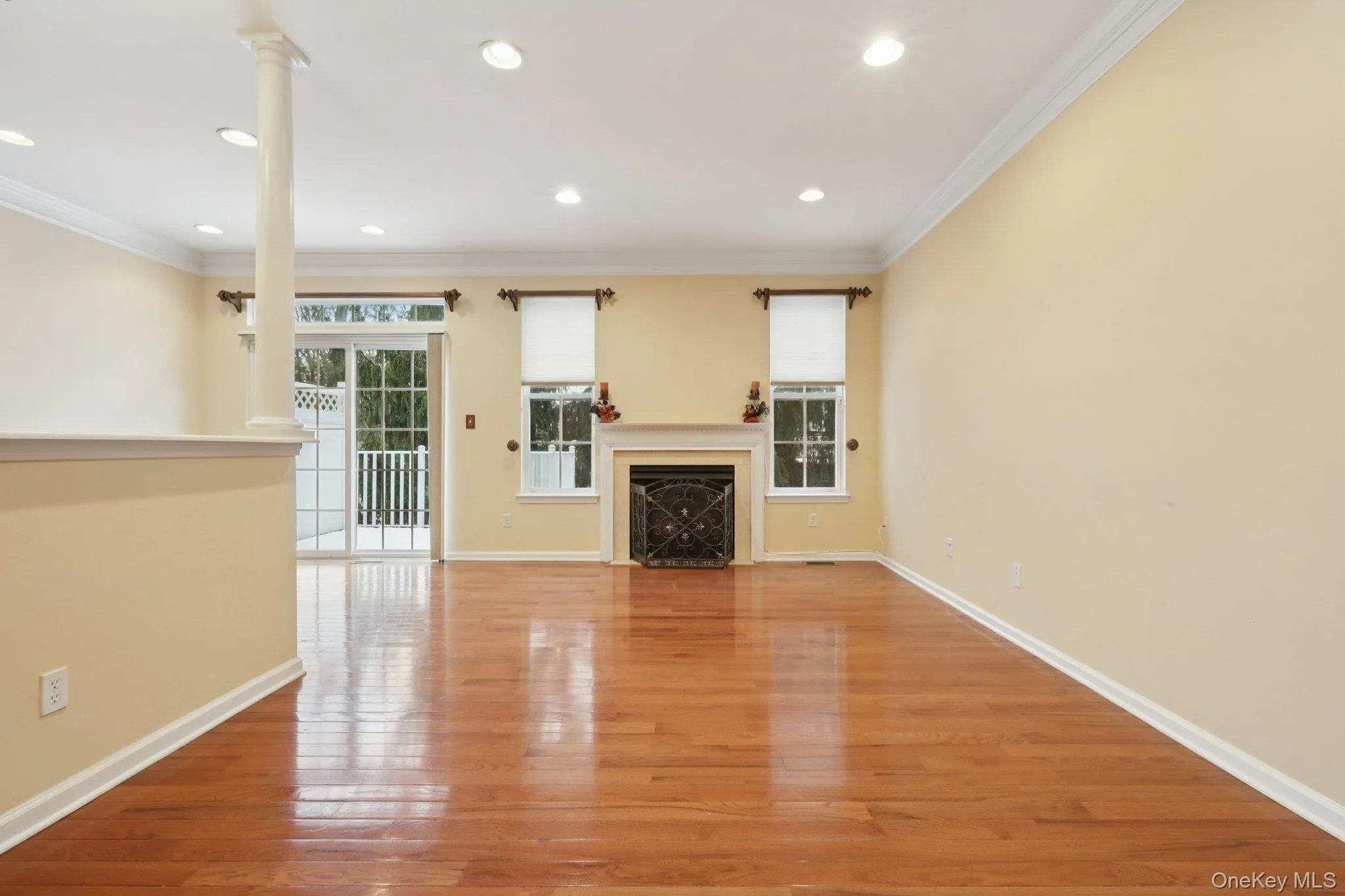 Living room featuring light wood flooring, a fireplace, crown molding, and recessed lighting Living room featuring light wood flooring, a fireplace, crown molding, and recessed lighting