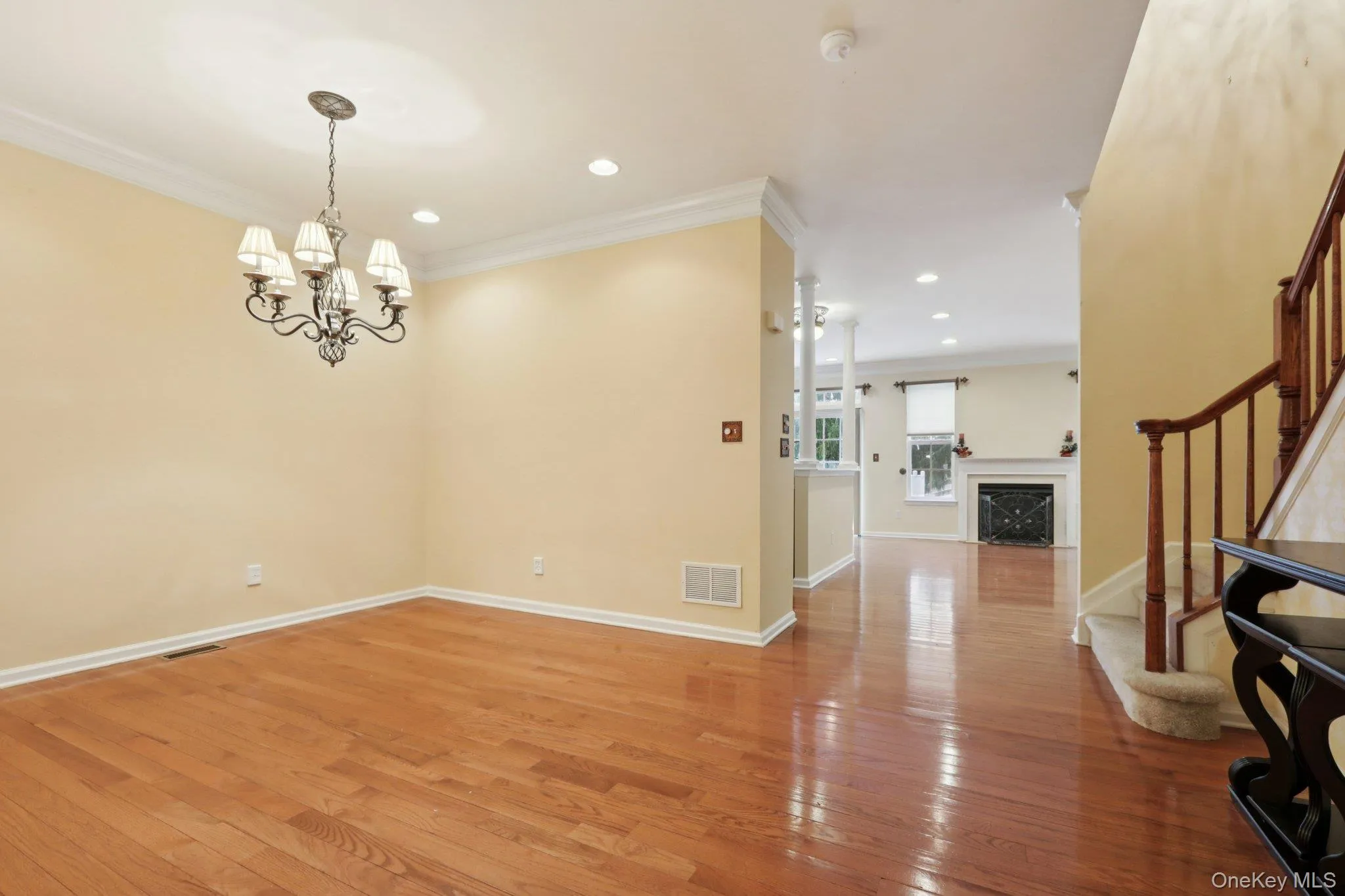 Dining room with stairway, crown molding, light wood-style flooring, a fireplace, and a chandelier Dining room with stairway, crown molding, light wood-style flooring, a fireplace, and a chandelier