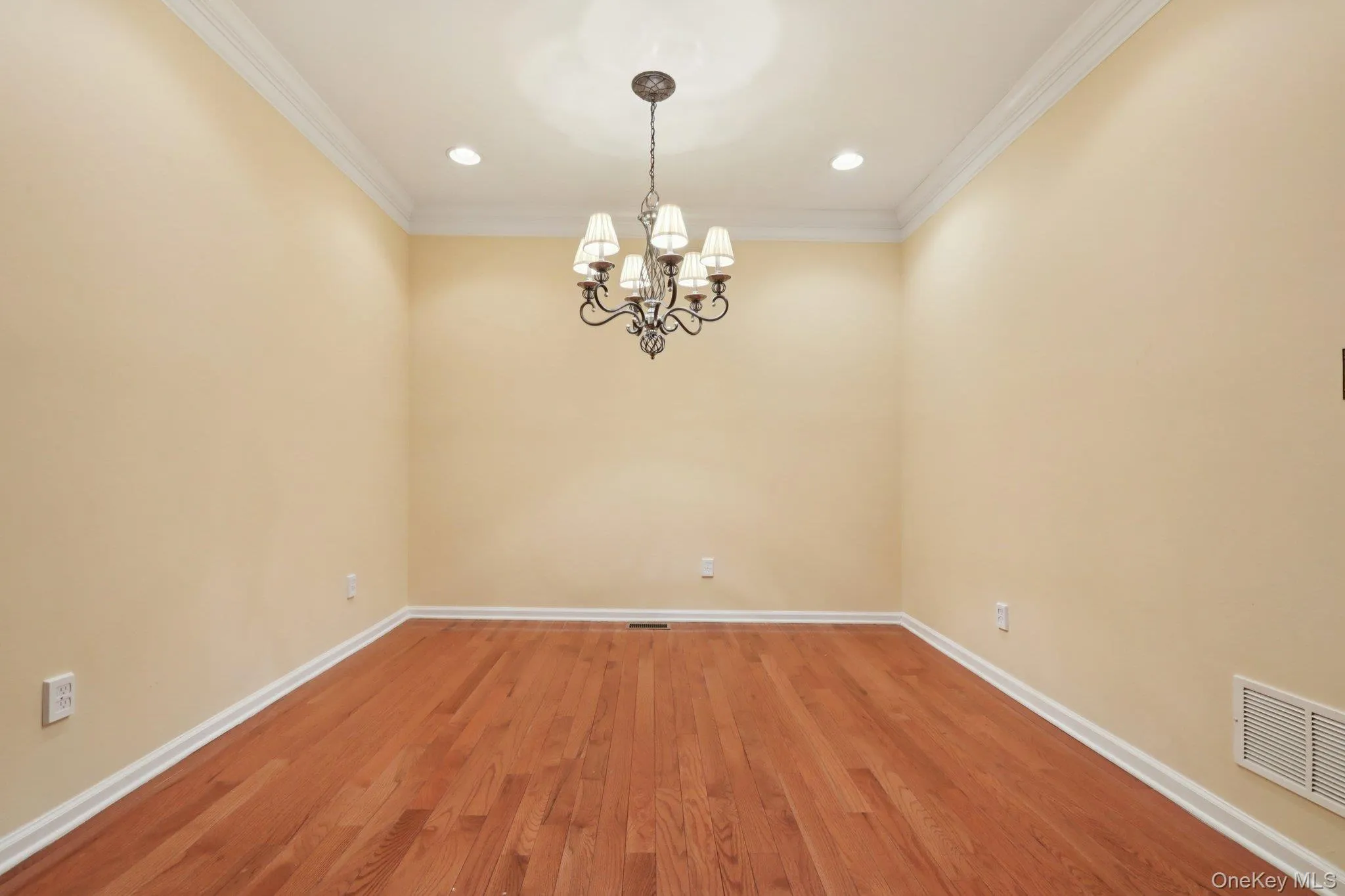 Empty room with ornamental molding, a chandelier, wood finished floors, and recessed lighting Empty room with ornamental molding, a chandelier, wood finished floors, and recessed lighting