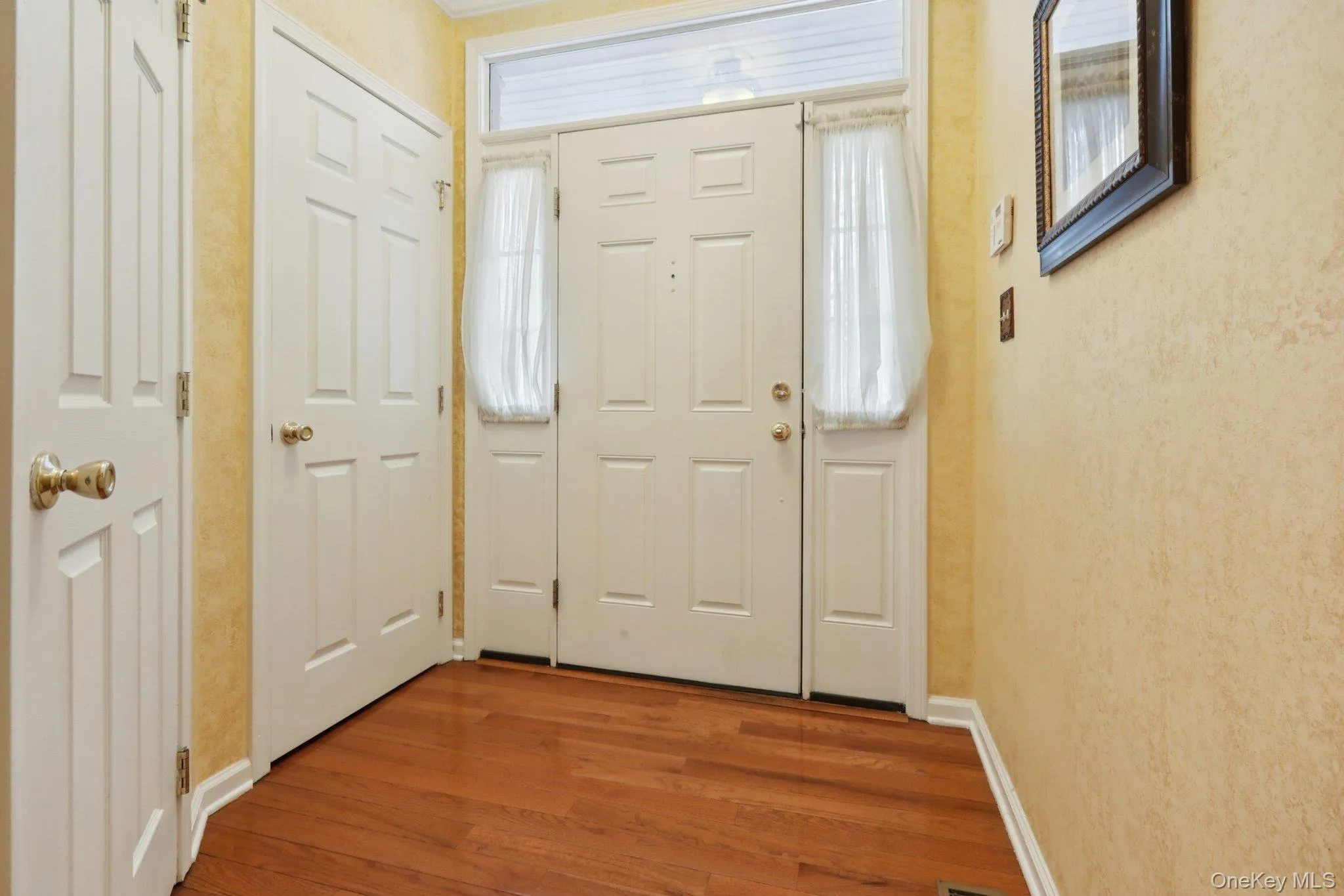 Foyer entrance featuring baseboards and wood finished floors Foyer entrance featuring baseboards and wood finished floors
