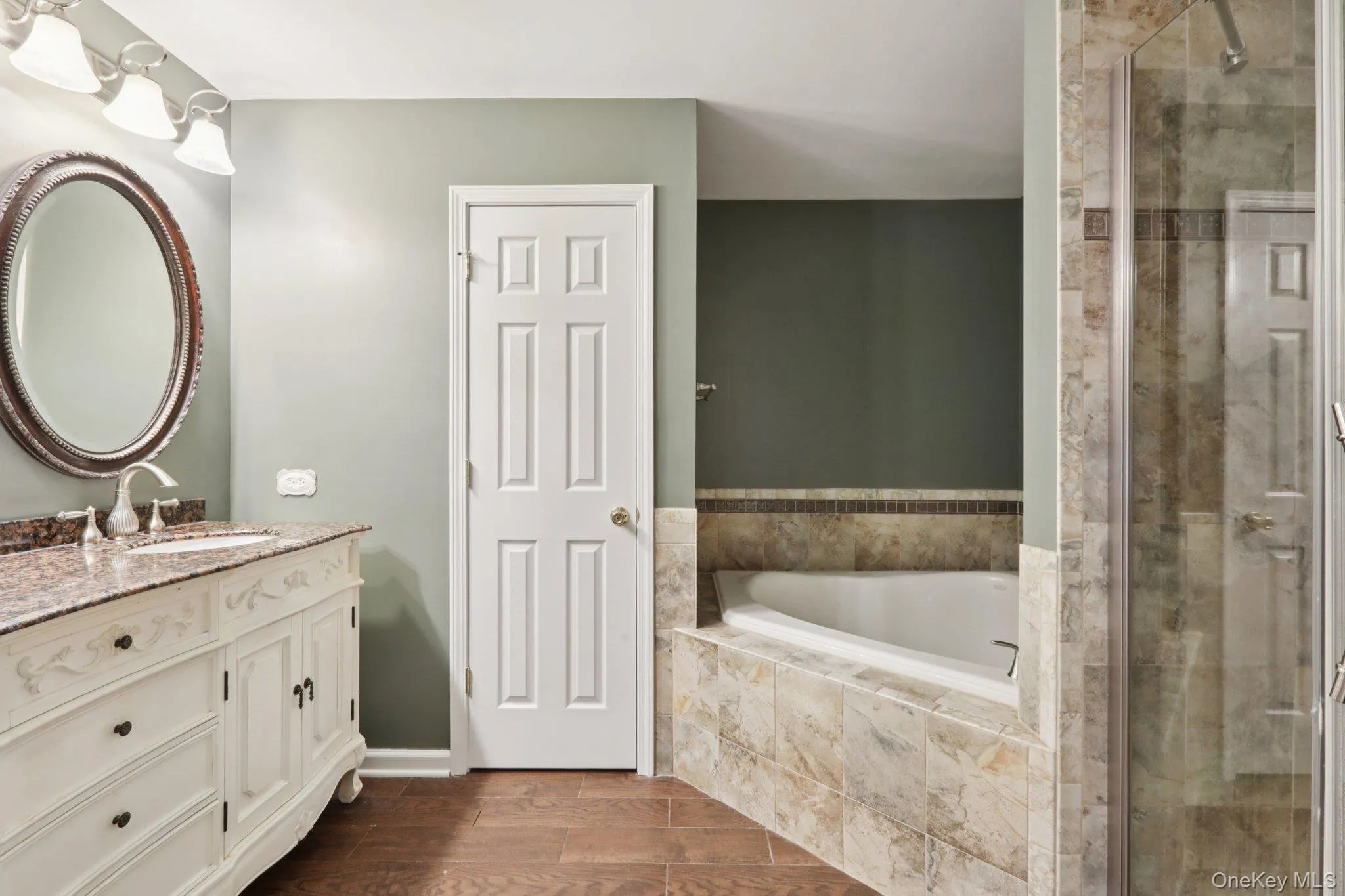 Bathroom with vanity, a garden tub, wood tiled floors, and a stall shower Bathroom with vanity, a garden tub, wood tiled floors, and a stall shower