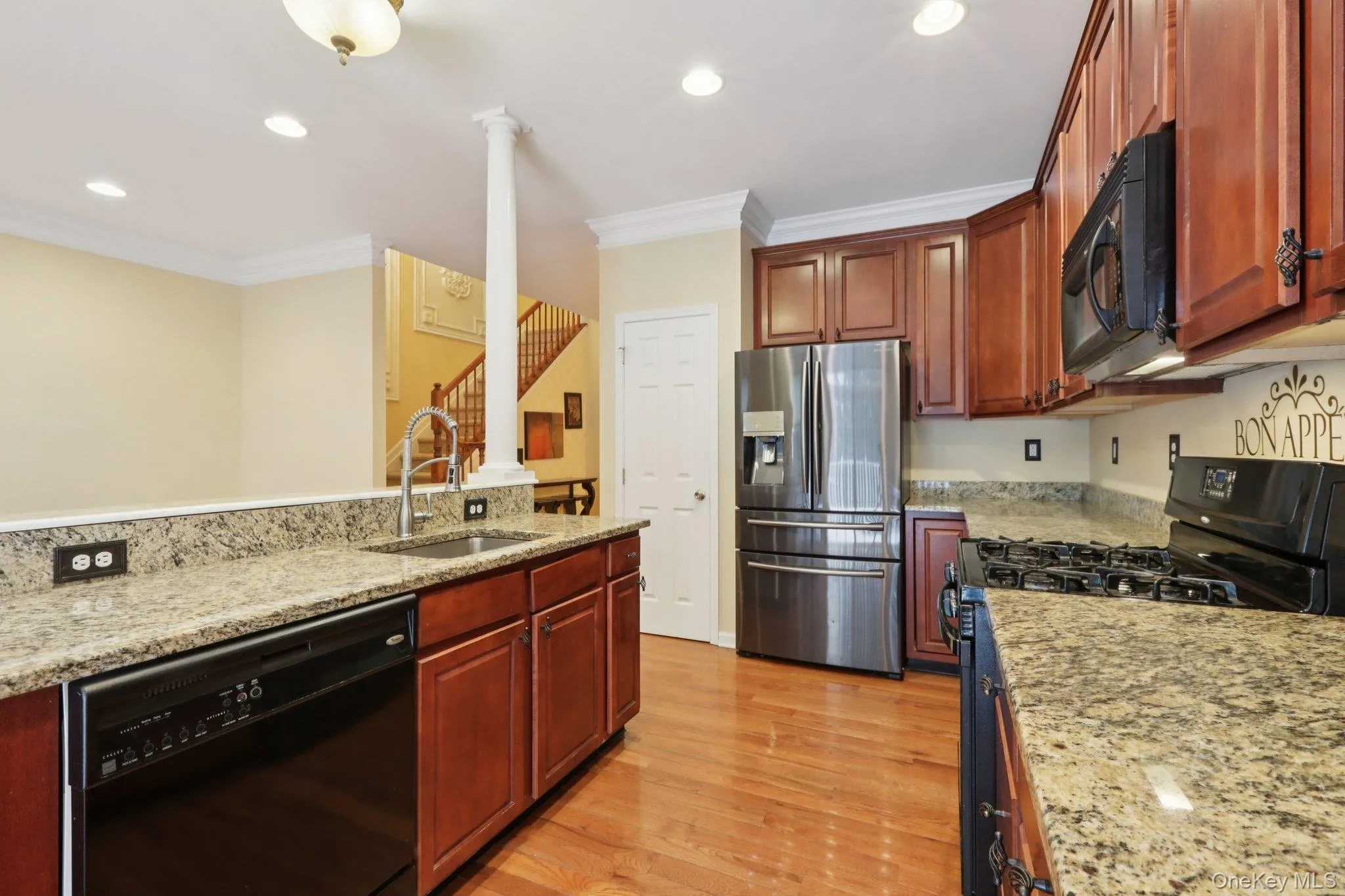Kitchen featuring black appliances, light stone counters, light Hardwood flooring, crown molding, and recessed lighting Kitchen featuring black appliances, light stone counters, light Hardwood flooring, crown molding, and recessed lighting