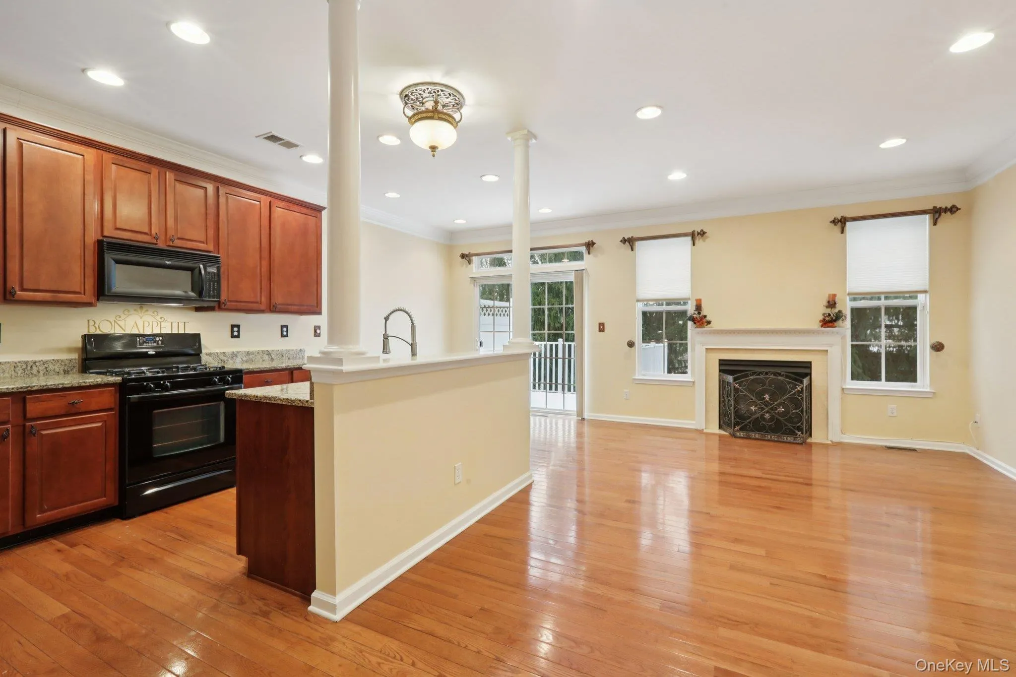 Kitchen with black appliances, ornamental molding, a fireplace, light hardwood flooring, and open floor plan Kitchen with black appliances, ornamental molding, a fireplace, light hardwood flooring, and open floor plan