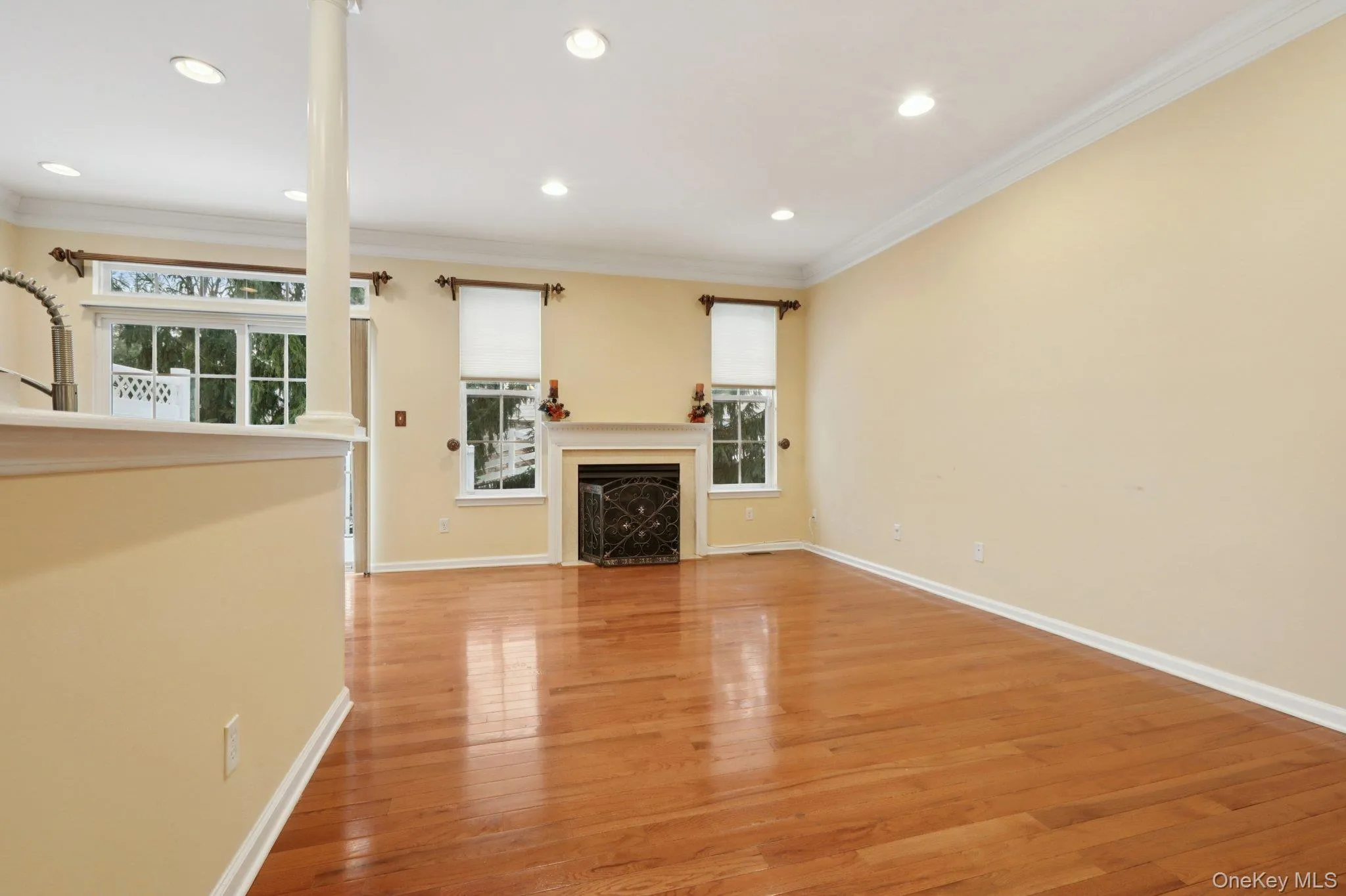 Living room with light wood flooring, crown molding, a fireplace, and recessed lighting Living room with light wood flooring, crown molding, a fireplace, and recessed lighting