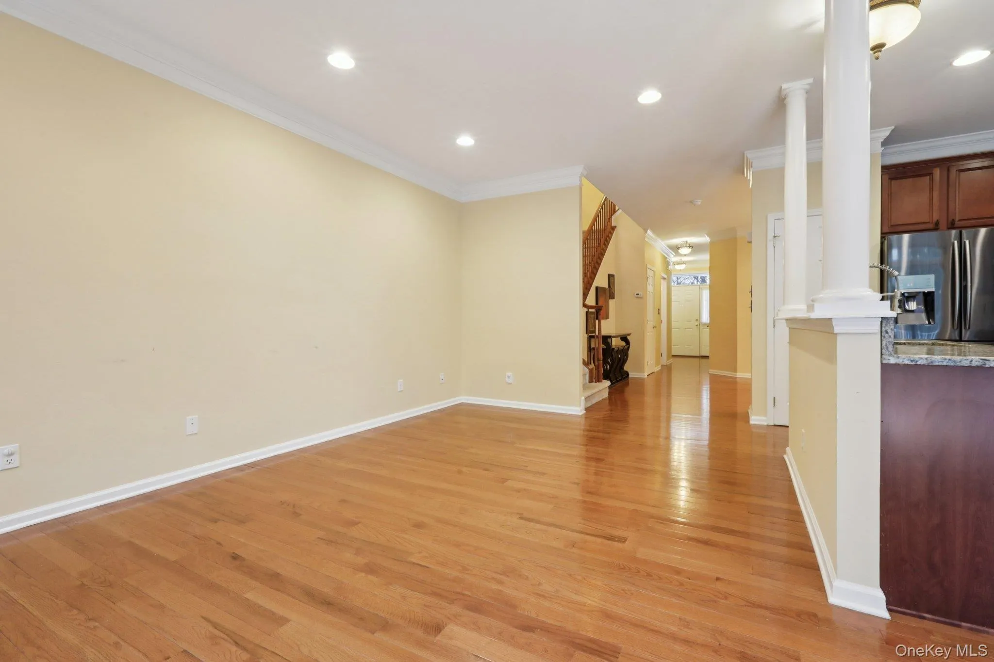 living room with crown molding, light wood finished floors, recessed lighting, and decorative columns living room with crown molding, light wood finished floors, recessed lighting, and decorative columns