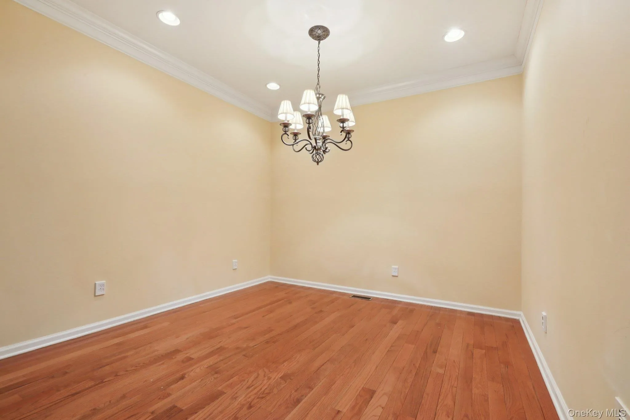 Spare room featuring wood finished floors, recessed lighting, a chandelier, and ornamental molding Spare room featuring wood finished floors, recessed lighting, a chandelier, and ornamental molding