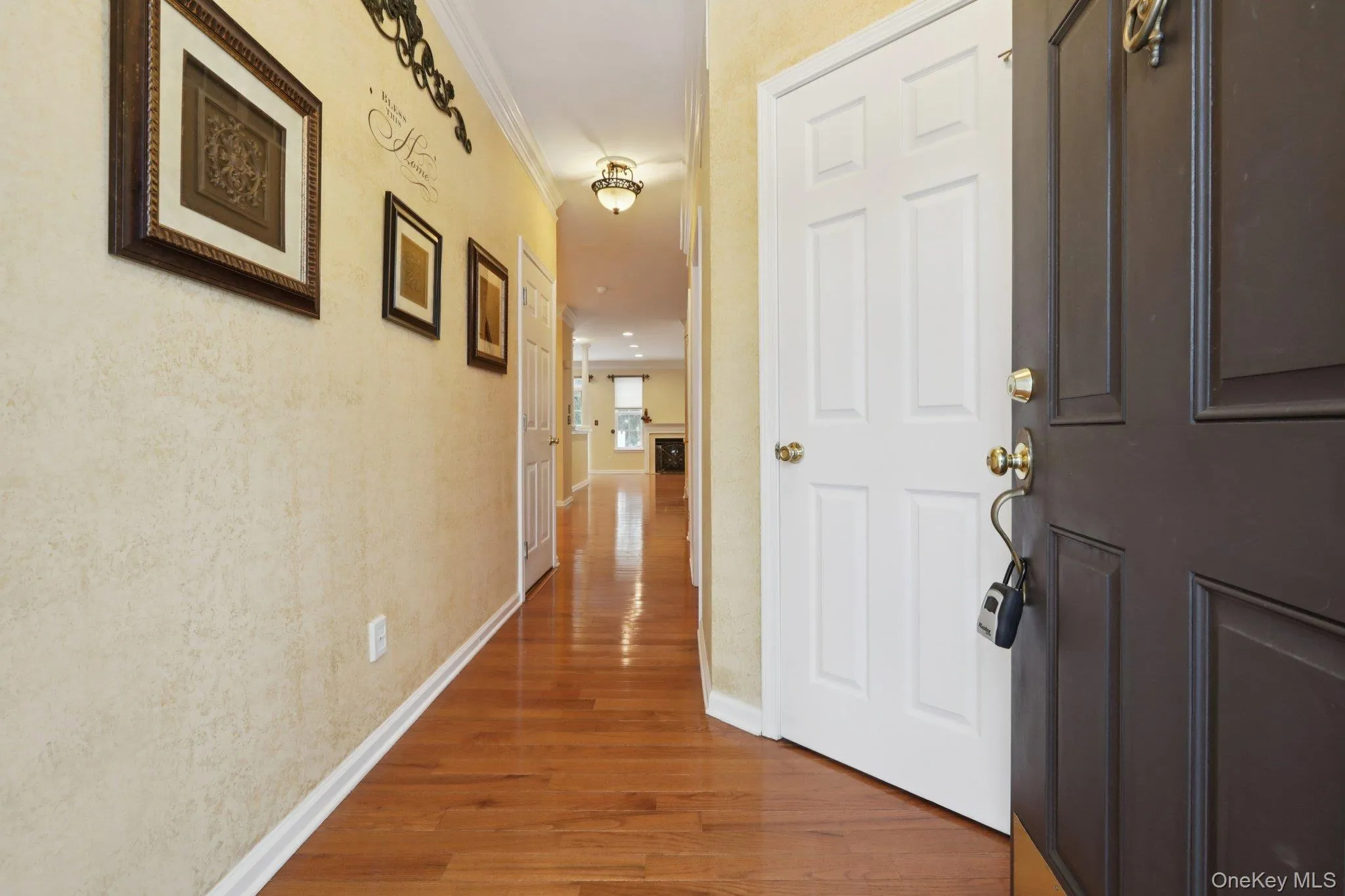 Hallway featuring light hardwood flooring and ornamental molding Hallway featuring light hardwood flooring and ornamental molding