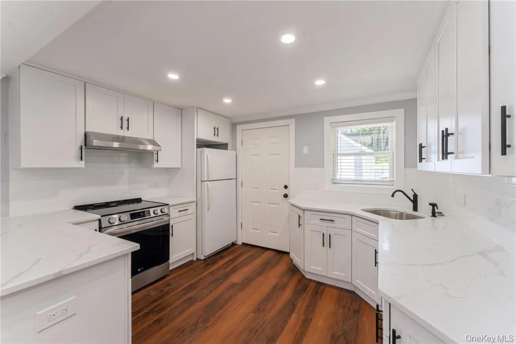 Kitchen with light stone countertops, electric range, white cabinets, recessed lighting, and crown molding Kitchen with light stone countertops, electric range, white cabinets, recessed lighting, and crown molding