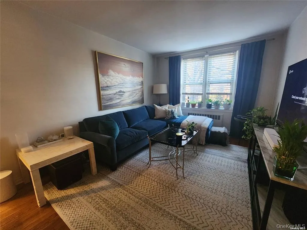 Living area featuring wood finished floors and radiator heating unit Living area featuring wood finished floors and radiator heating unit