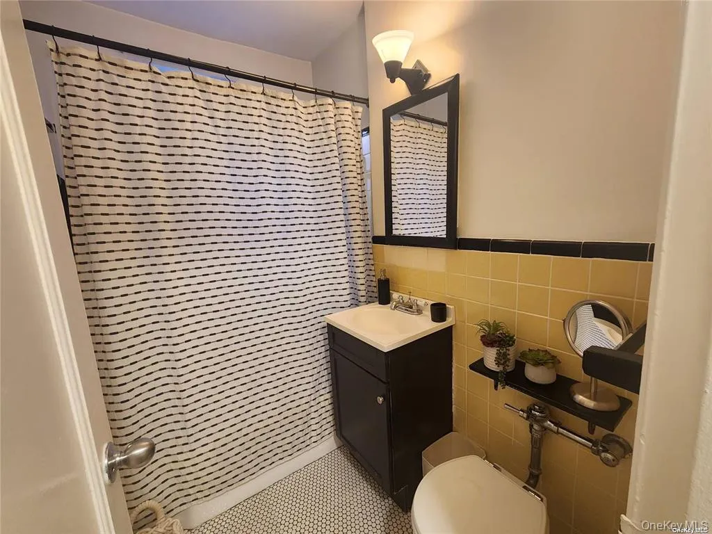Bathroom with vanity, tile walls, and a shower with shower curtain Bathroom with vanity, tile walls, and a shower with shower curtain