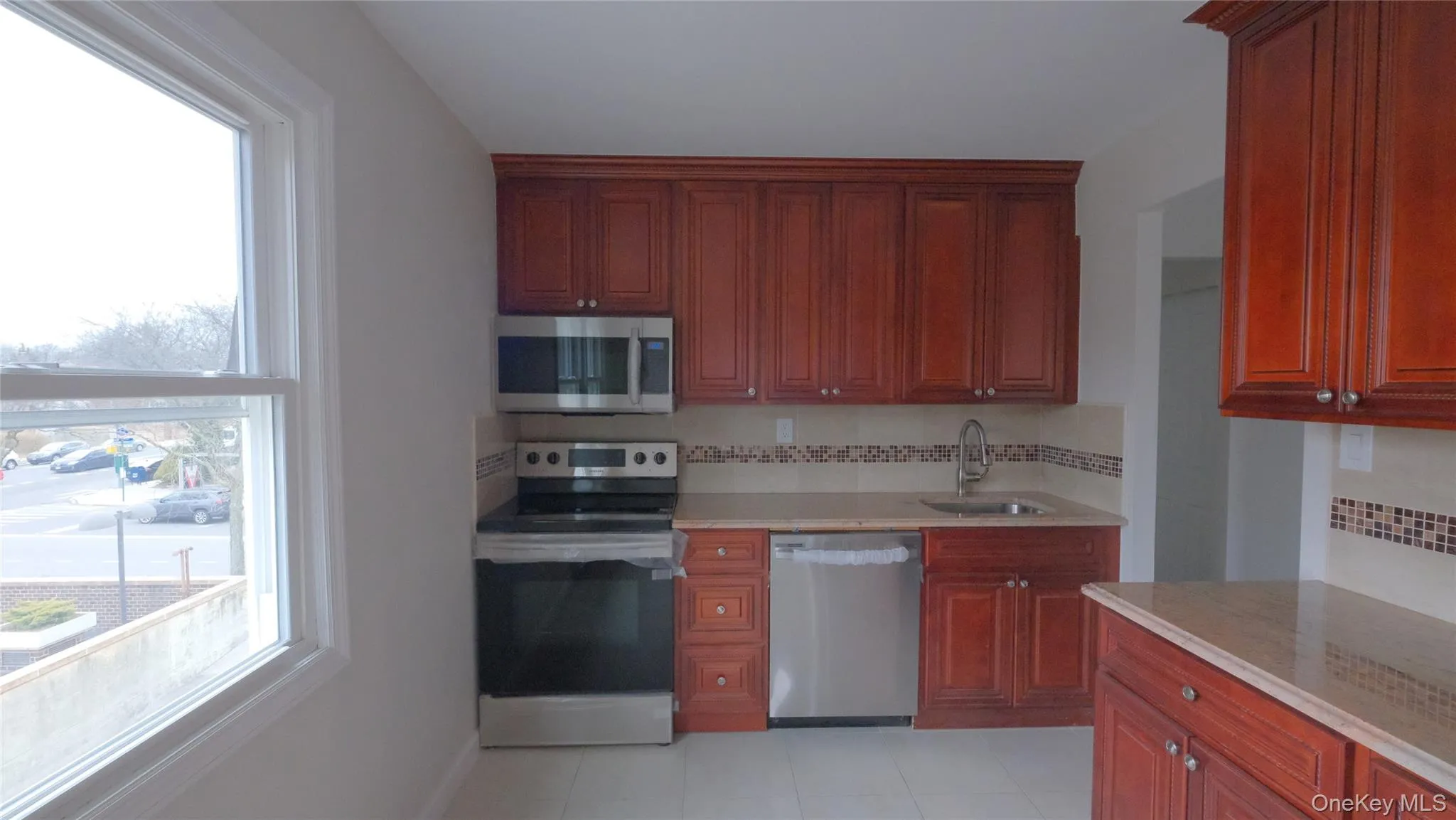Kitchen featuring appliances with stainless steel finishes, light stone countertops, decorative backsplash, and light tile patterned floors Kitchen featuring appliances with stainless steel finishes, light stone countertops, decorative backsplash, and light tile patterned floors