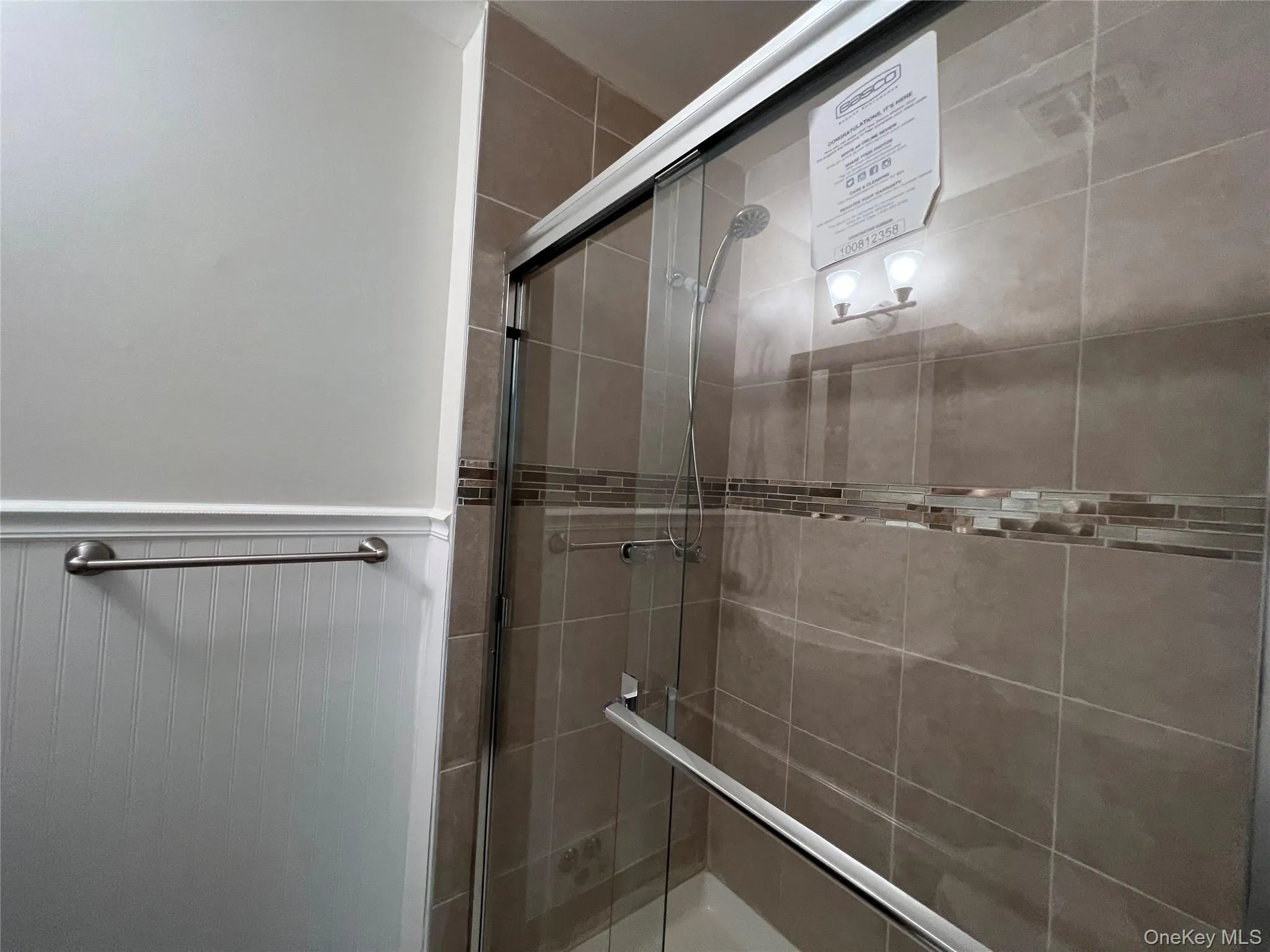 Bathroom featuring a shower stall and wainscoting Bathroom featuring a shower stall and wainscoting