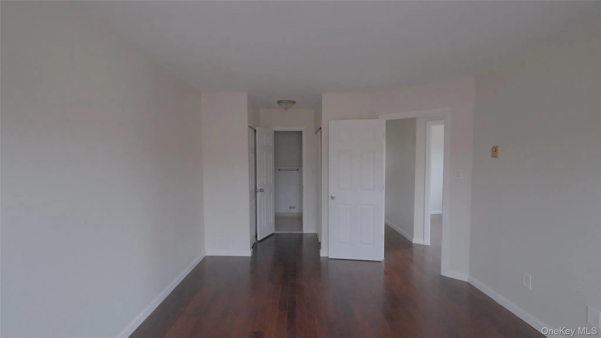 Empty room with baseboards and dark wood-style flooring Empty room with baseboards and dark wood-style flooring