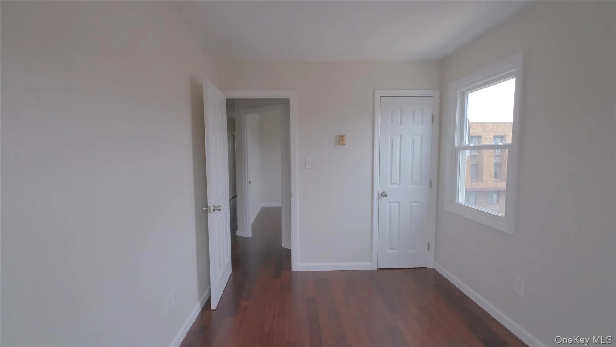 Unfurnished bedroom with baseboards and dark wood-style flooring Unfurnished bedroom with baseboards and dark wood-style flooring