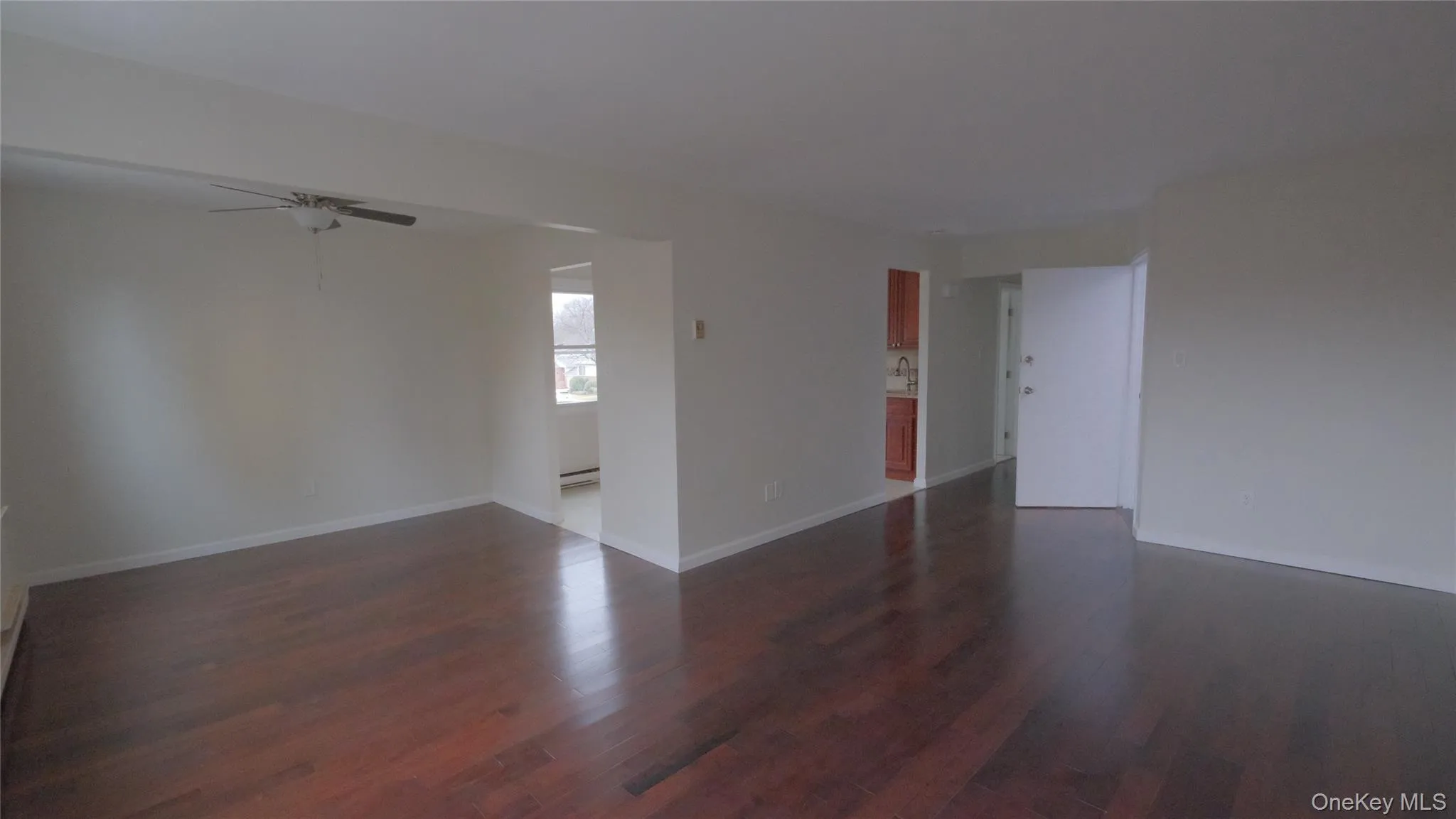 Spare room featuring a ceiling fan, dark wood-type flooring, and a baseboard radiator Spare room featuring a ceiling fan, dark wood-type flooring, and a baseboard radiator