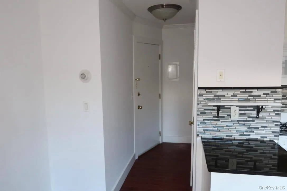 Hallway with crown molding and dark wood-style floors Hallway with crown molding and dark wood-style floors