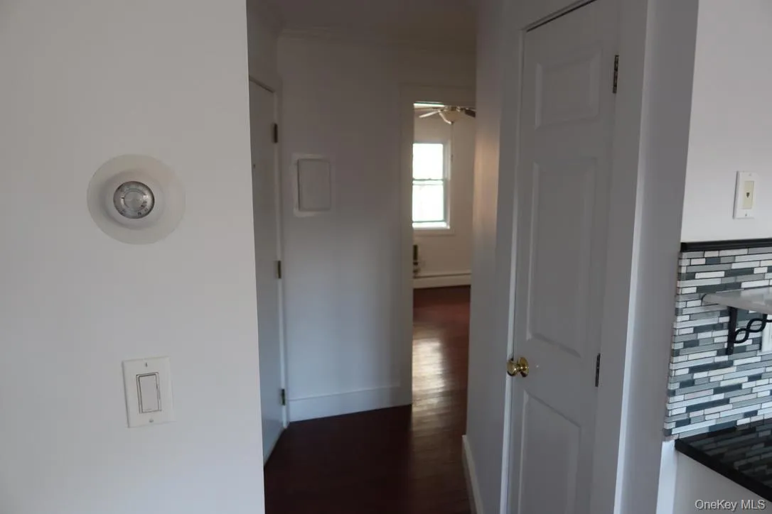Hallway featuring a baseboard heating unit and dark wood-style floors Hallway featuring a baseboard heating unit and dark wood-style floors