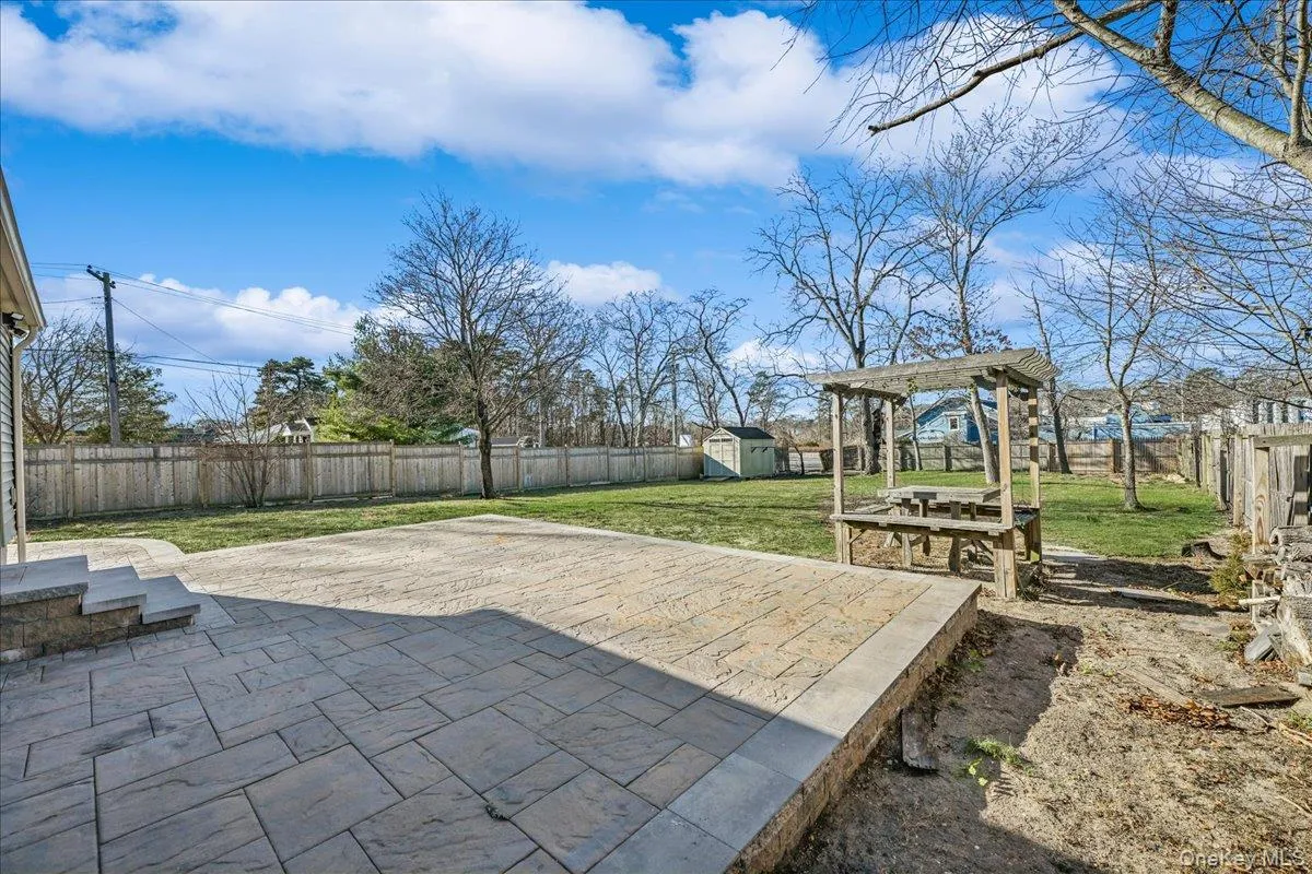 Fenced backyard featuring a patio, a storage unit, and a pergola Fenced backyard featuring a patio, a storage unit, and a pergola