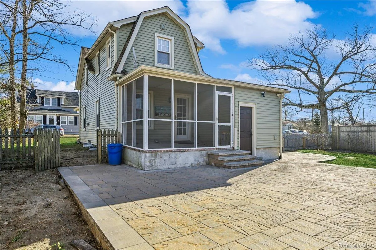 Back of house with a sunroom, a patio, and a gambrel roof Back of house with a sunroom, a patio, and a gambrel roof