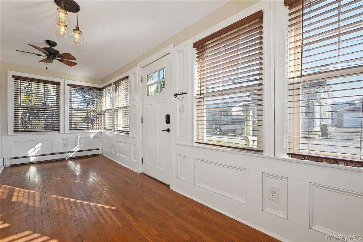 Entryway featuring a baseboard heating unit, dark wood-style floors, a decorative wall, and a ceiling fan Entryway featuring a baseboard heating unit, dark wood-style floors, a decorative wall, and a ceiling fan