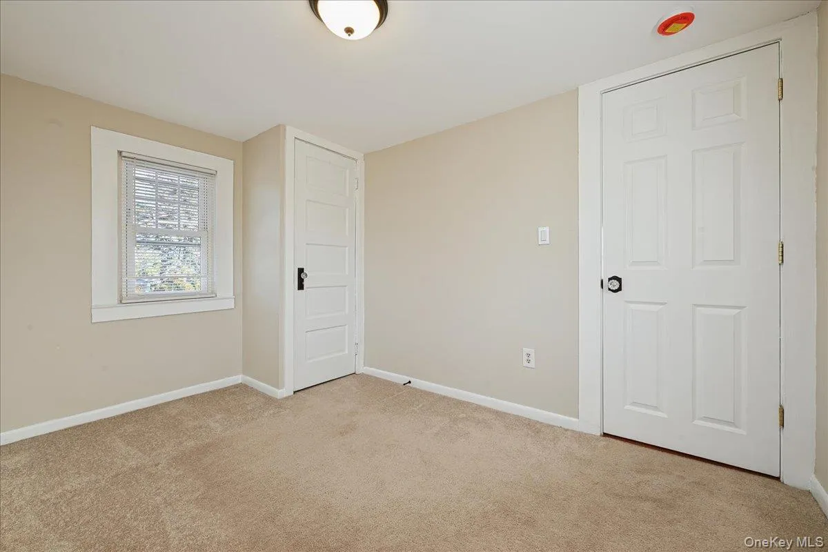 Unfurnished bedroom with light colored carpet and baseboards Unfurnished bedroom with light colored carpet and baseboards