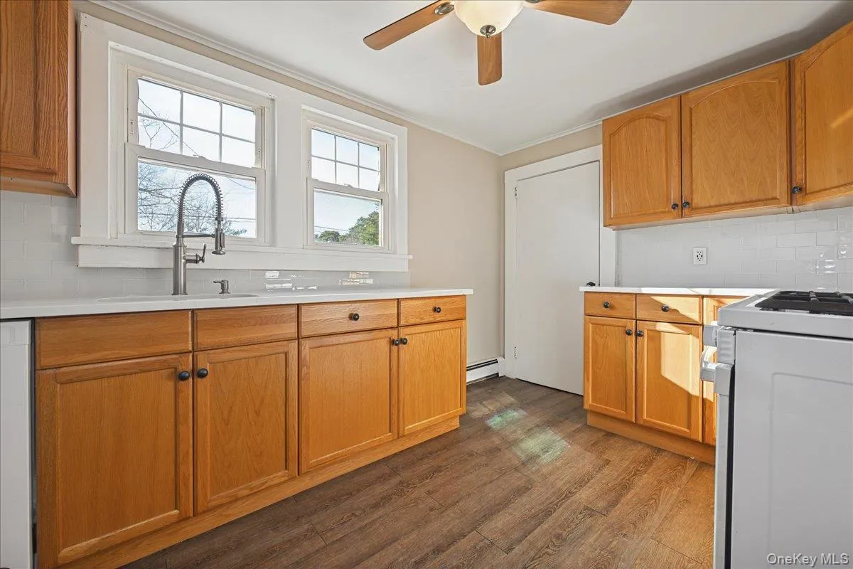 Kitchen with tasteful backsplash, gas range, light countertops, a ceiling fan, and crown molding Kitchen with tasteful backsplash, gas range, light countertops, a ceiling fan, and crown molding
