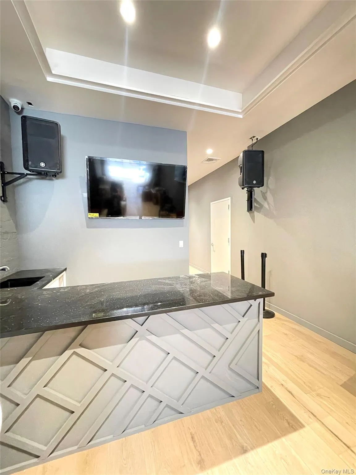 Kitchen with dark stone countertops, baseboards, a raised ceiling, visible vents, and wood finished floors Kitchen with dark stone countertops, baseboards, a raised ceiling, visible vents, and wood finished floors